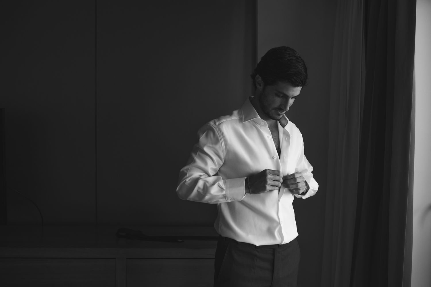 Monochrome image of person adjusting formal attire while getting ready.