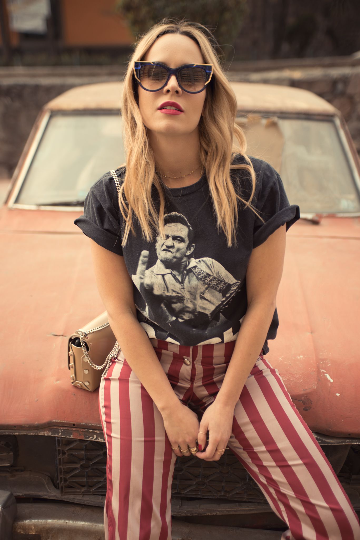 Retro-styled portrait with vintage car and striped pants against muted background.