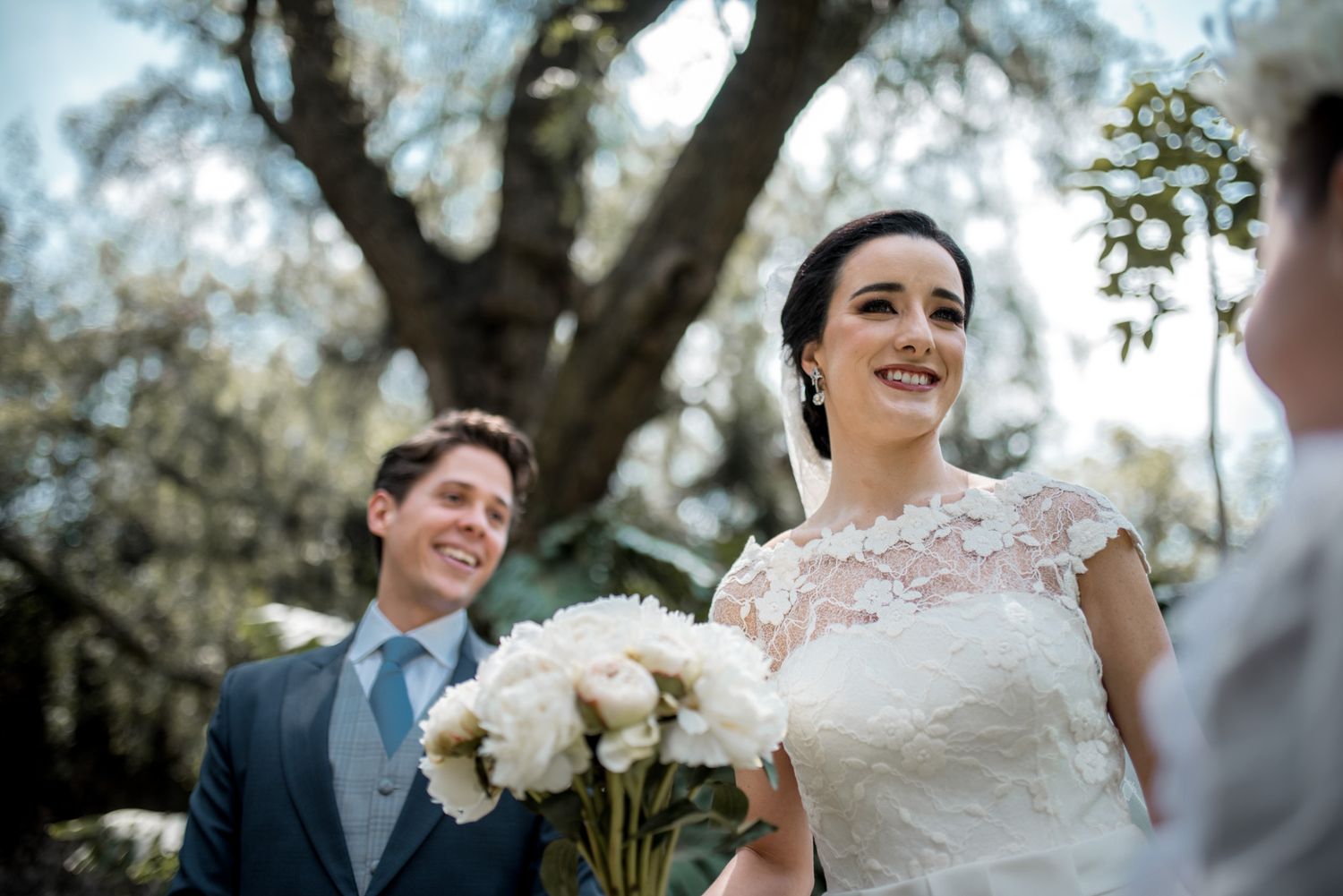 Joyful wedding ceremony moment outdoors under large oak tree.