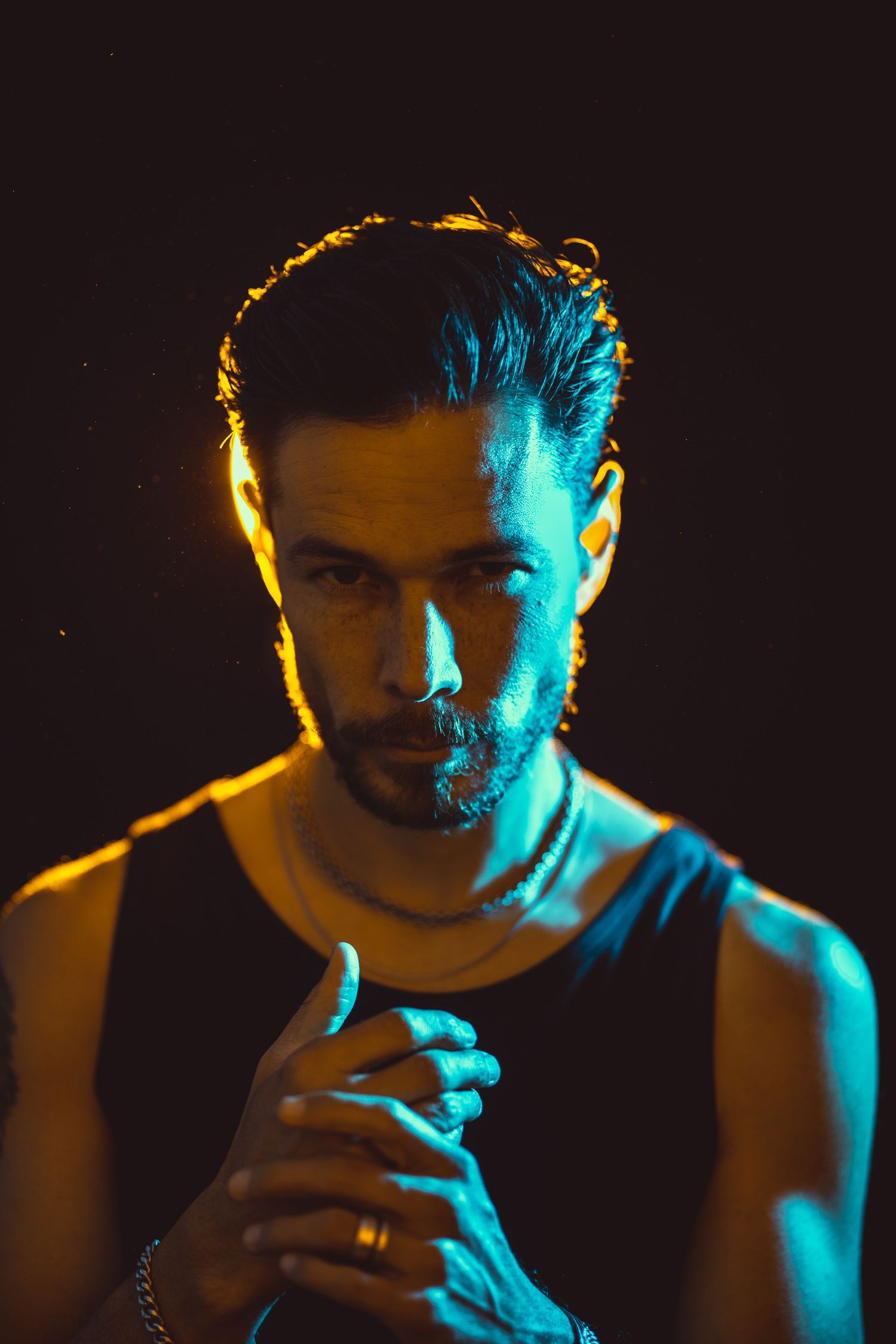 Dramatic male portrait with blue and orange split lighting against dark background.