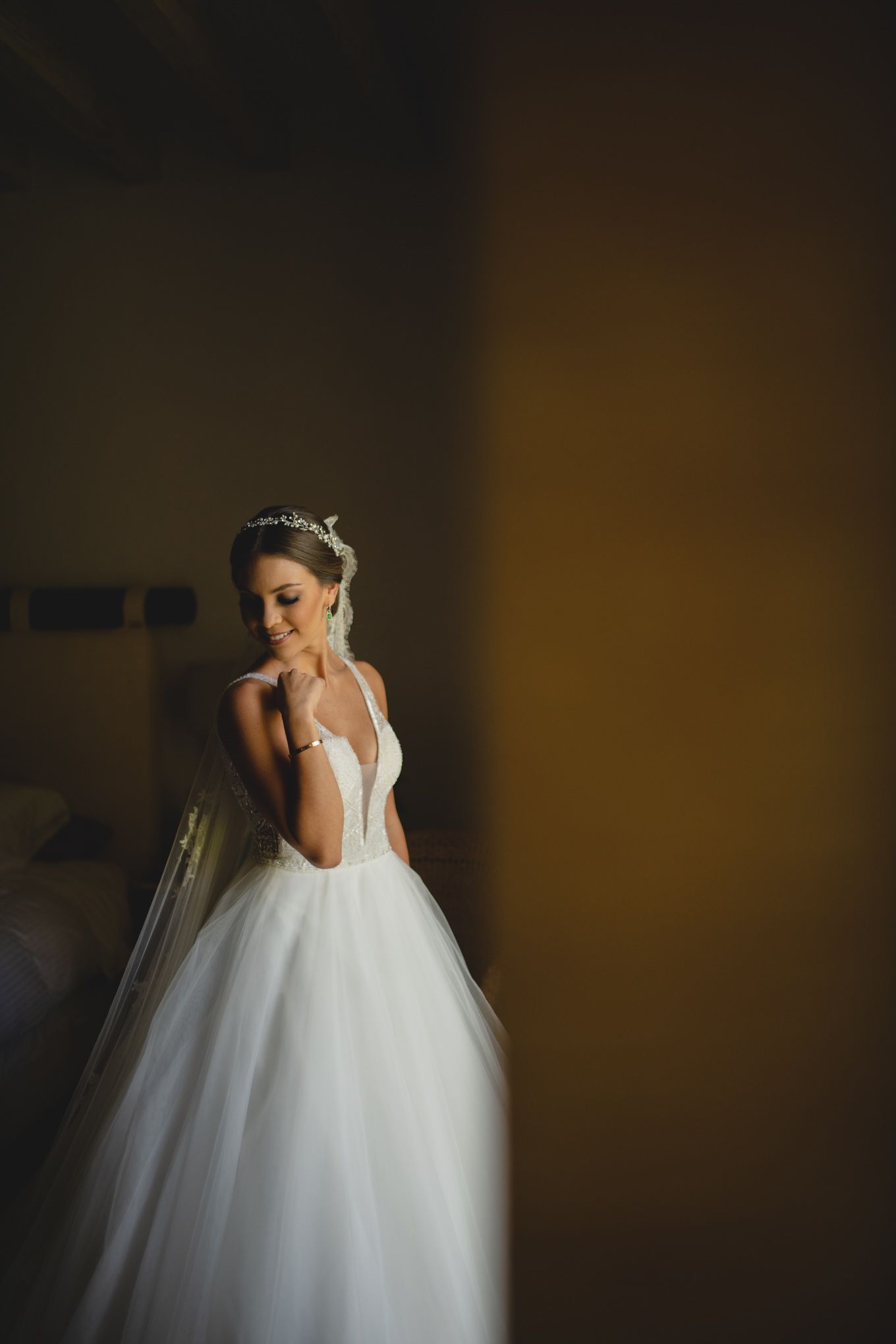 Dramatic portrait of a bride in white ballgown wedding dress posing elegantly against a dark atmospheric background.