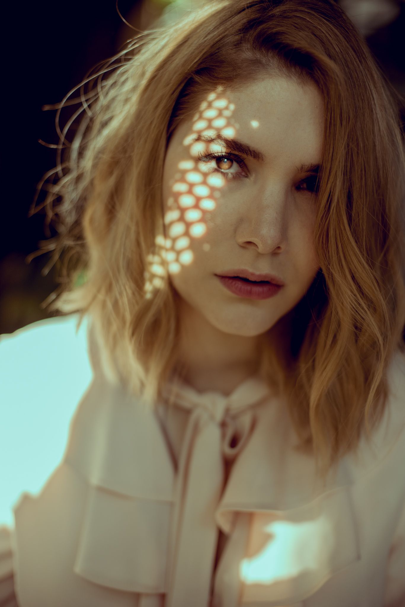 Artistic portrait with honeycomb light pattern cast across model's face.