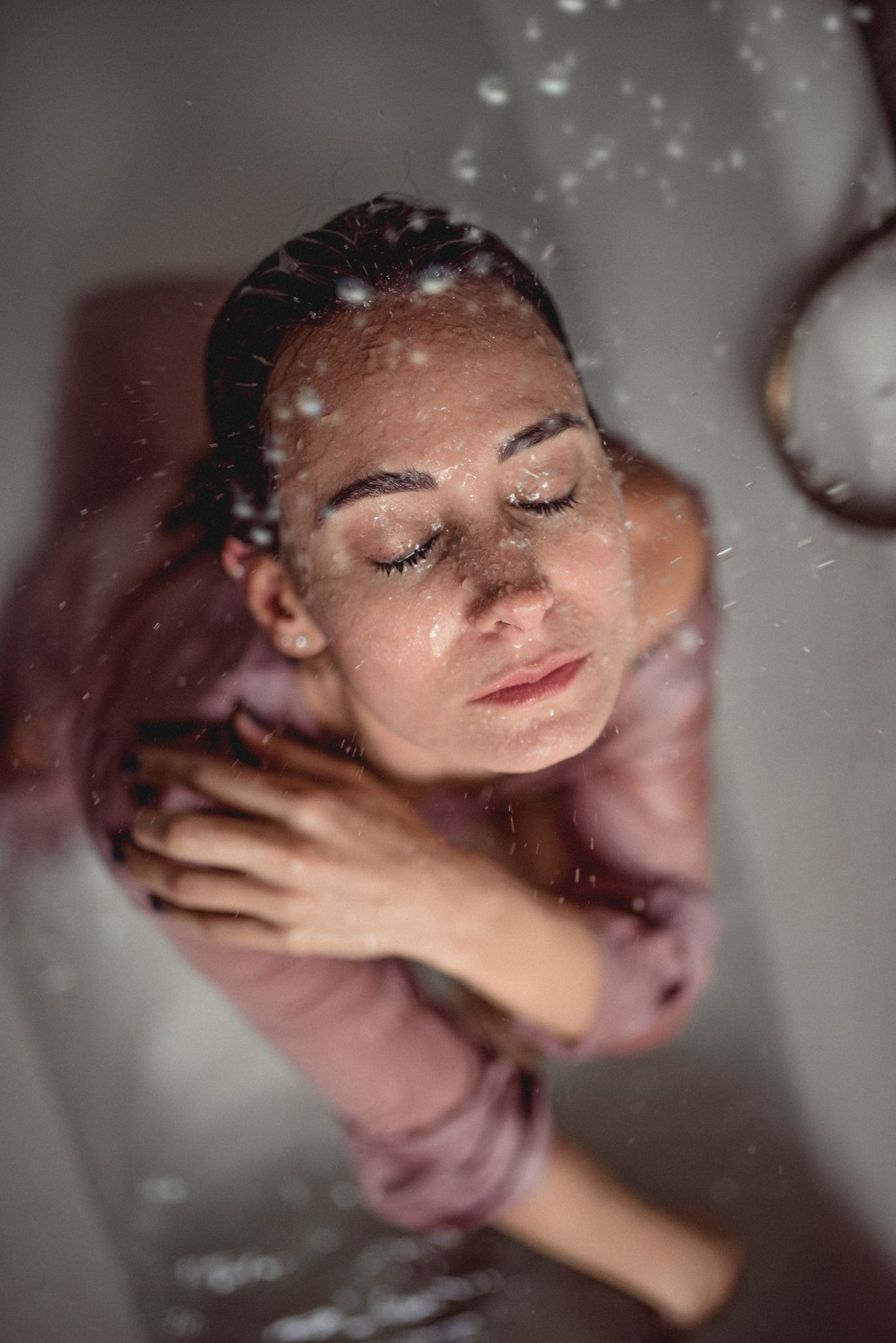 Ethereal portrait with water droplets creating dreamy atmosphere in muted tones.