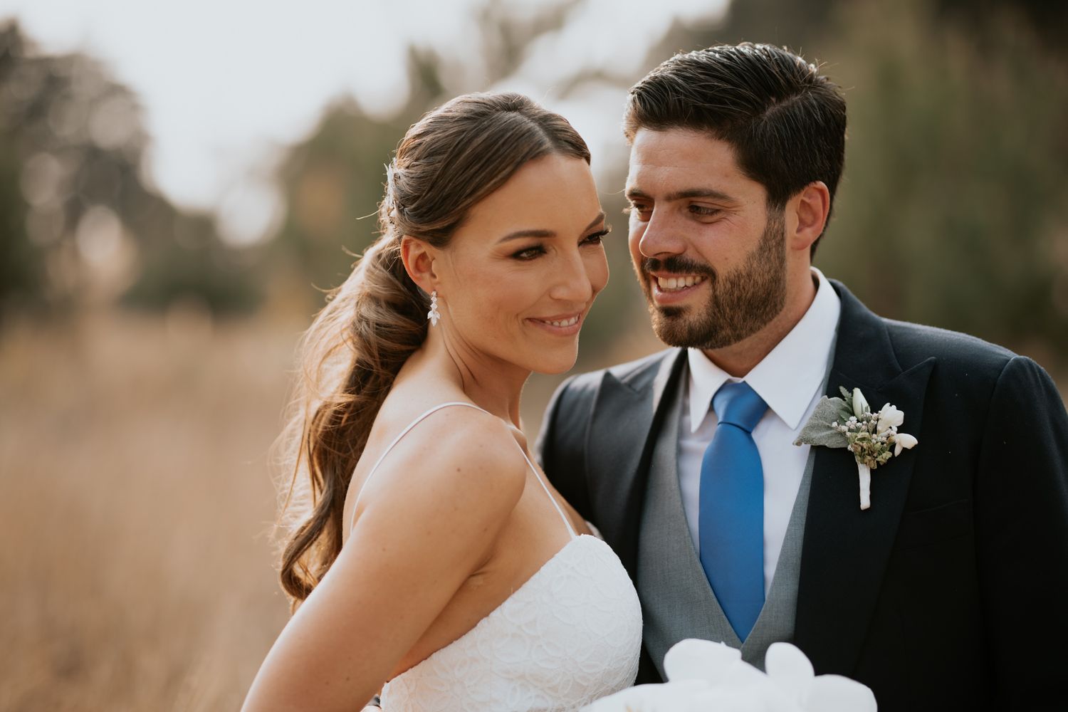 Romantic wedding couple shares intimate moment in sunlit field.