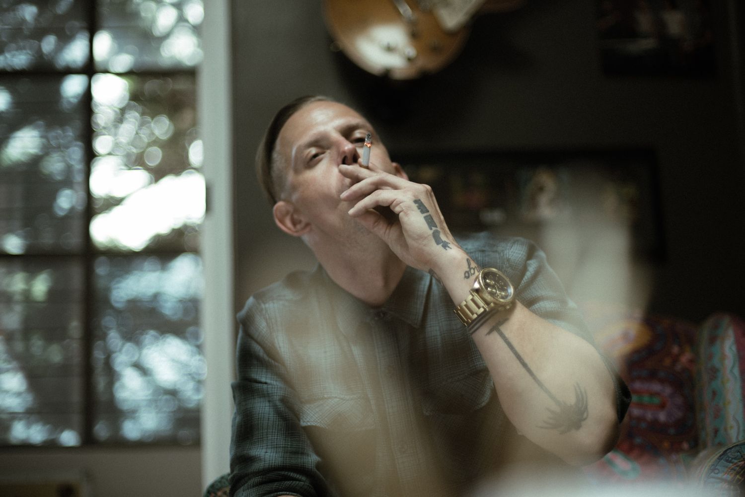 Atmospheric portrait of someone exhaling smoke in moody lighting with shallow depth of field.