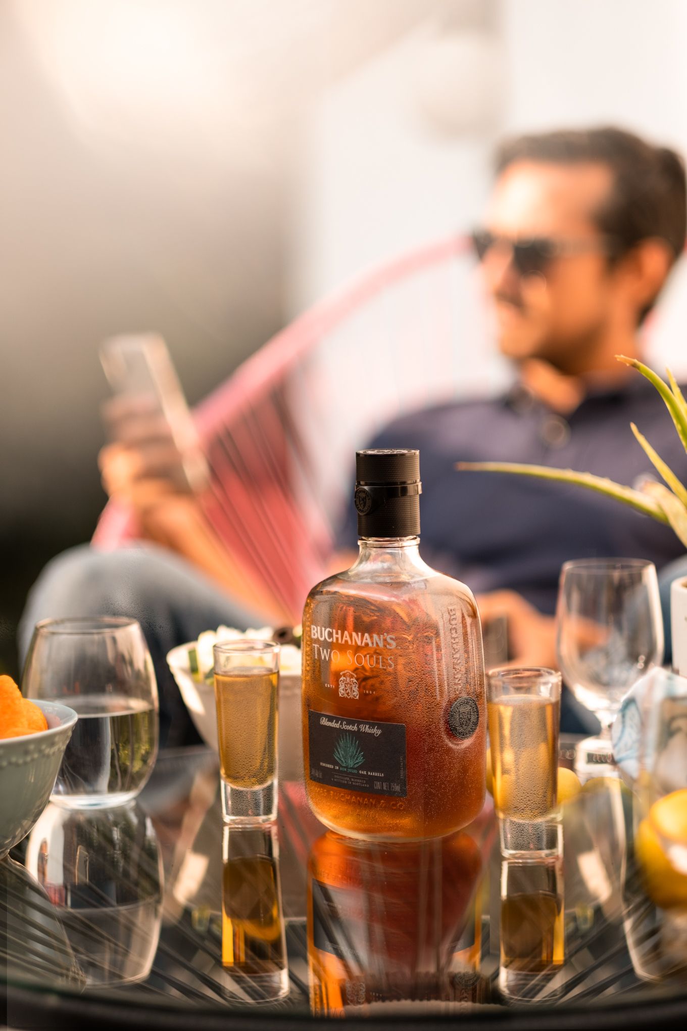 Close-up shot of bourbon bottles and glasses on a table during a festive gathering with blurred background.
