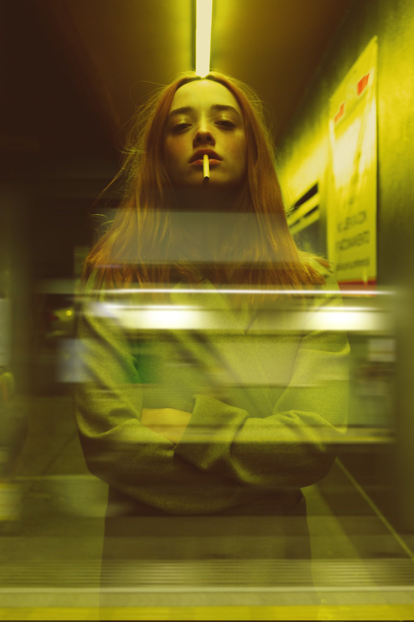 Atmospheric yellow-tinted portrait through reflective glass with cigarette smoke.