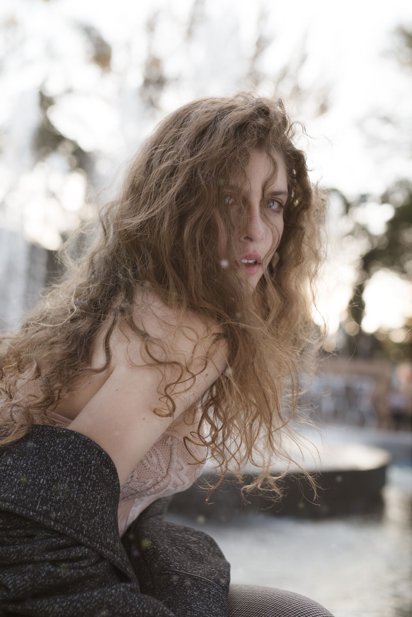 Dreamy outdoor portrait with flowing curls and delicate lighting creating a romantic mood.