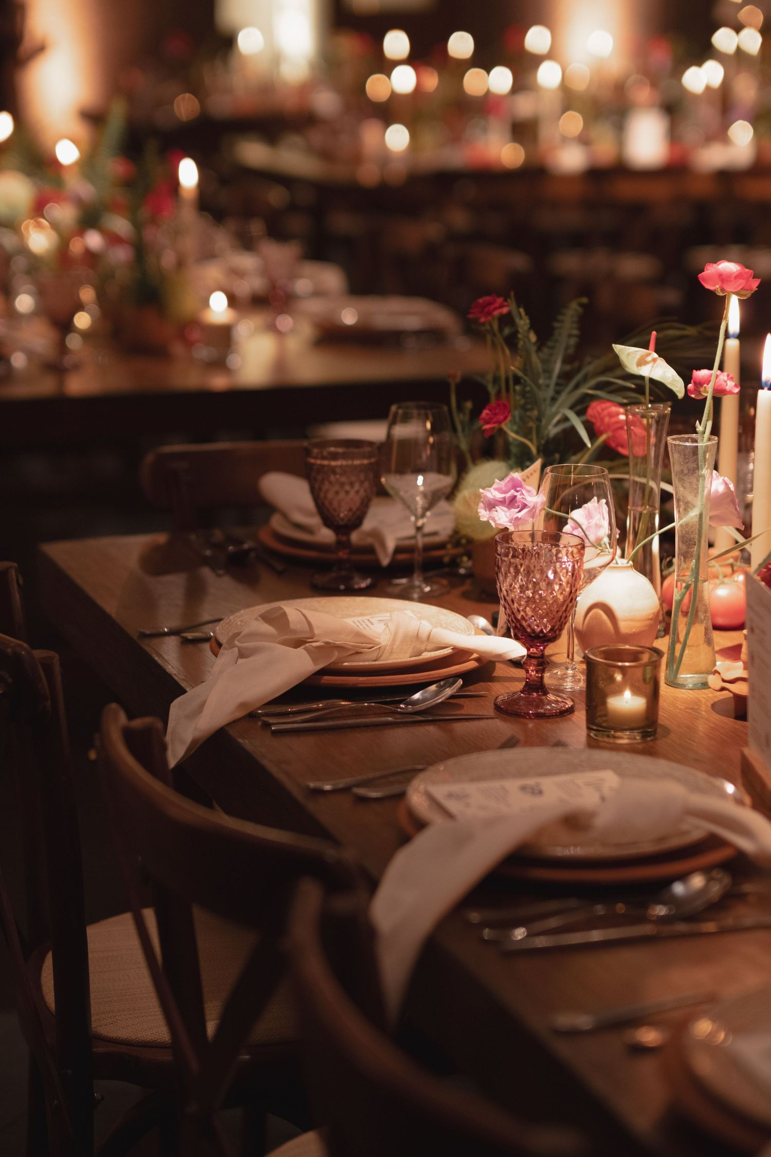 Elegant wedding reception table setting with candlelight, flowers and crystal glassware.