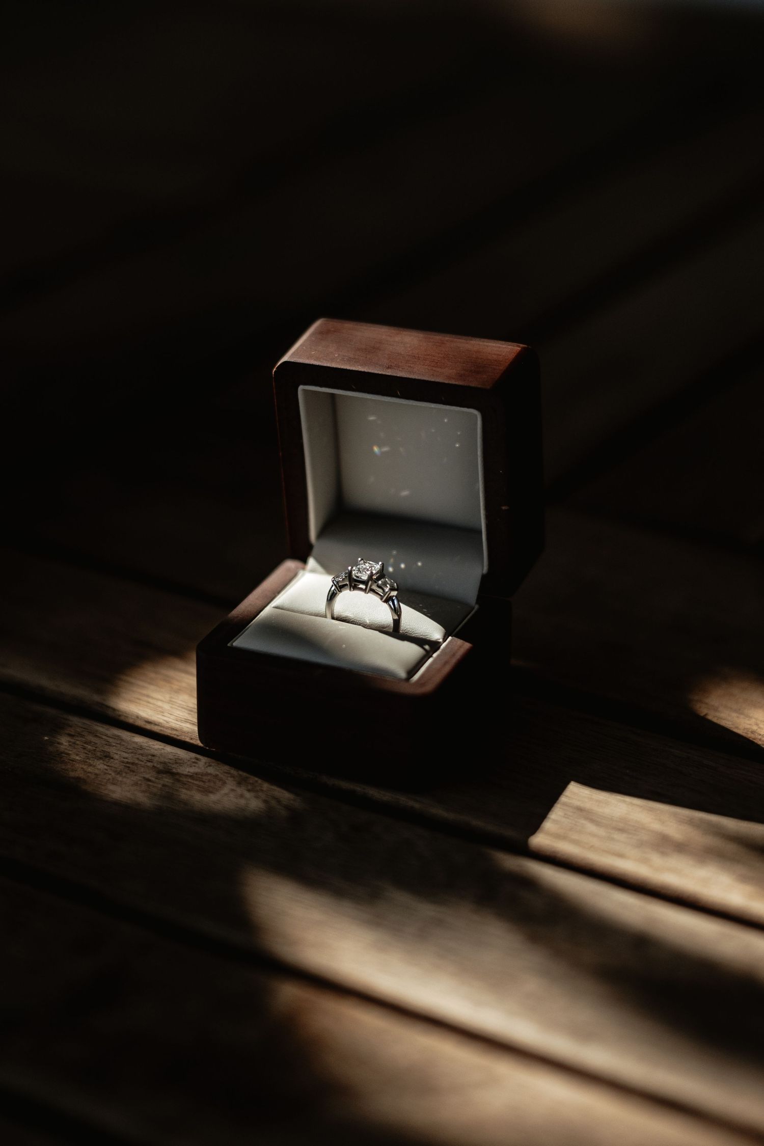 Diamond engagement ring in elegant dark box with dramatic lighting.