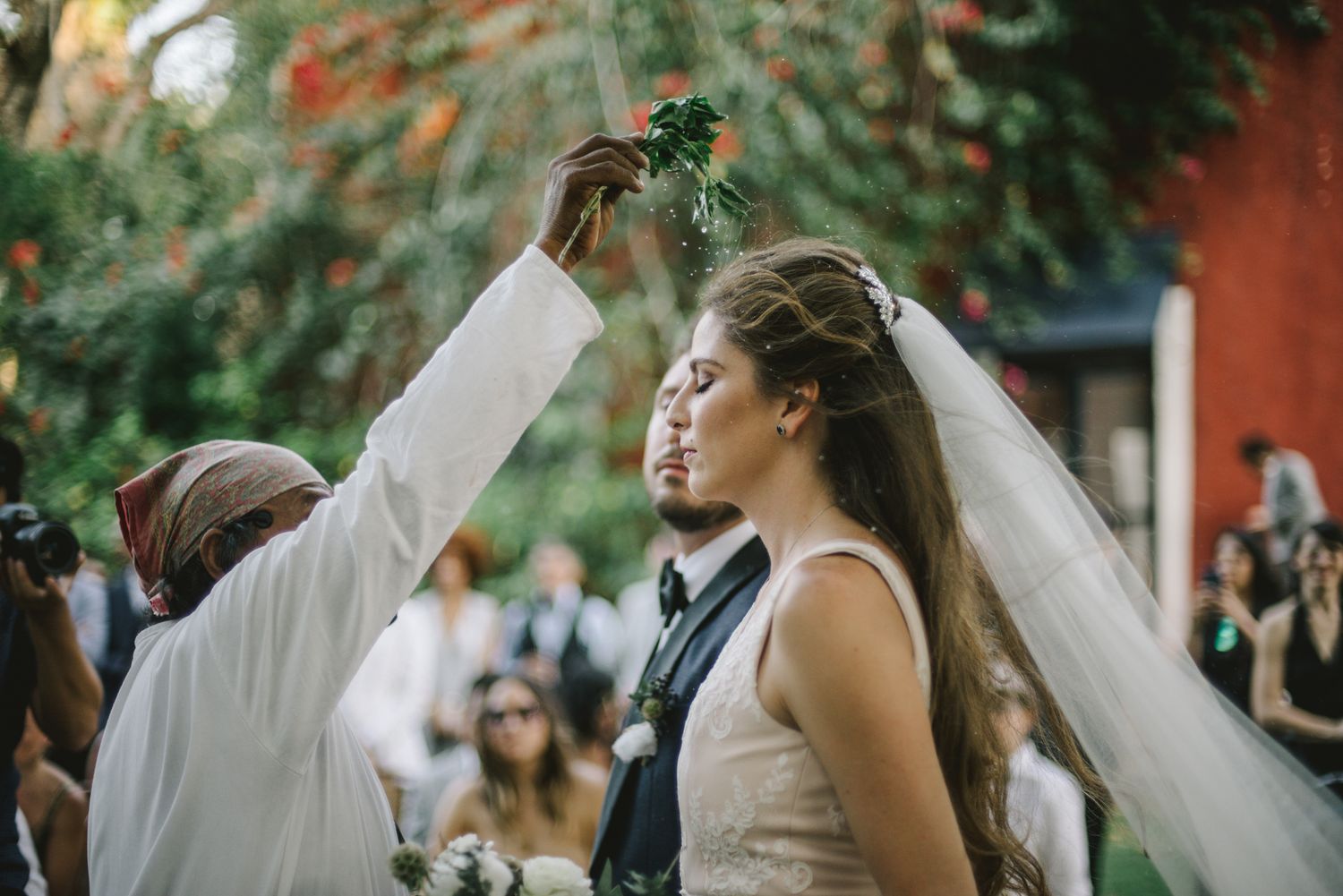 A joyful wedding ceremony moment captured outdoors with a bridal veil flowing in a garden setting.