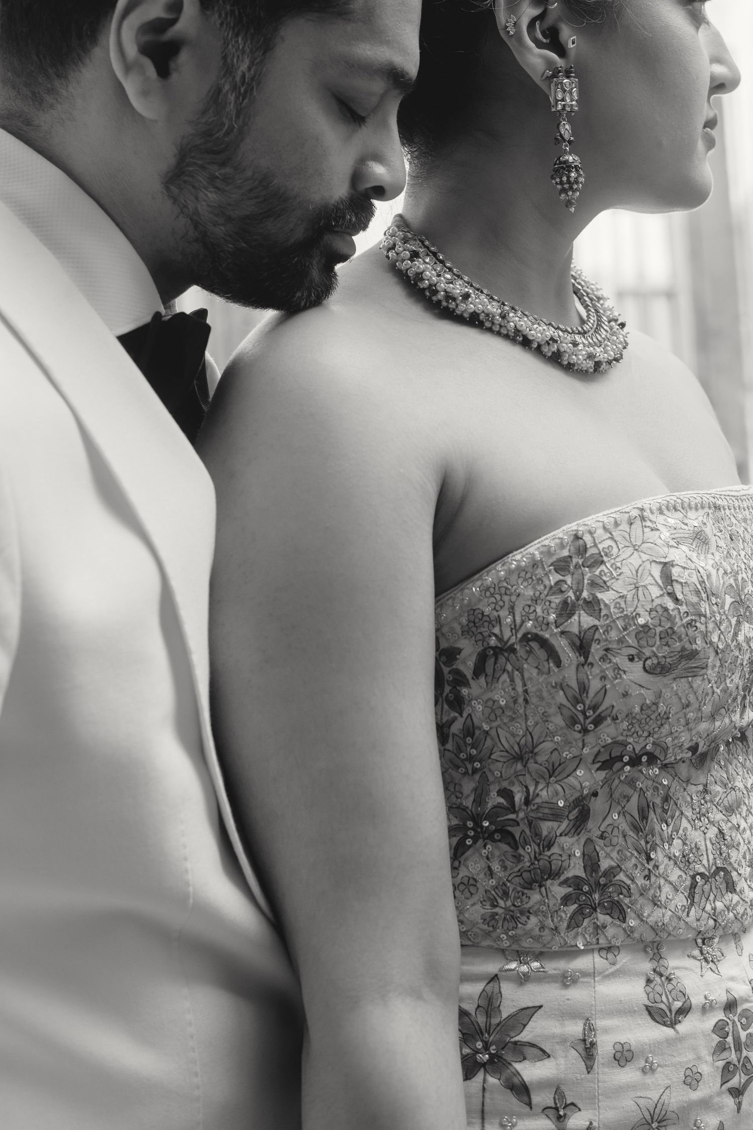 Elegant black and white close-up of formal attire and intricate jewelry details.