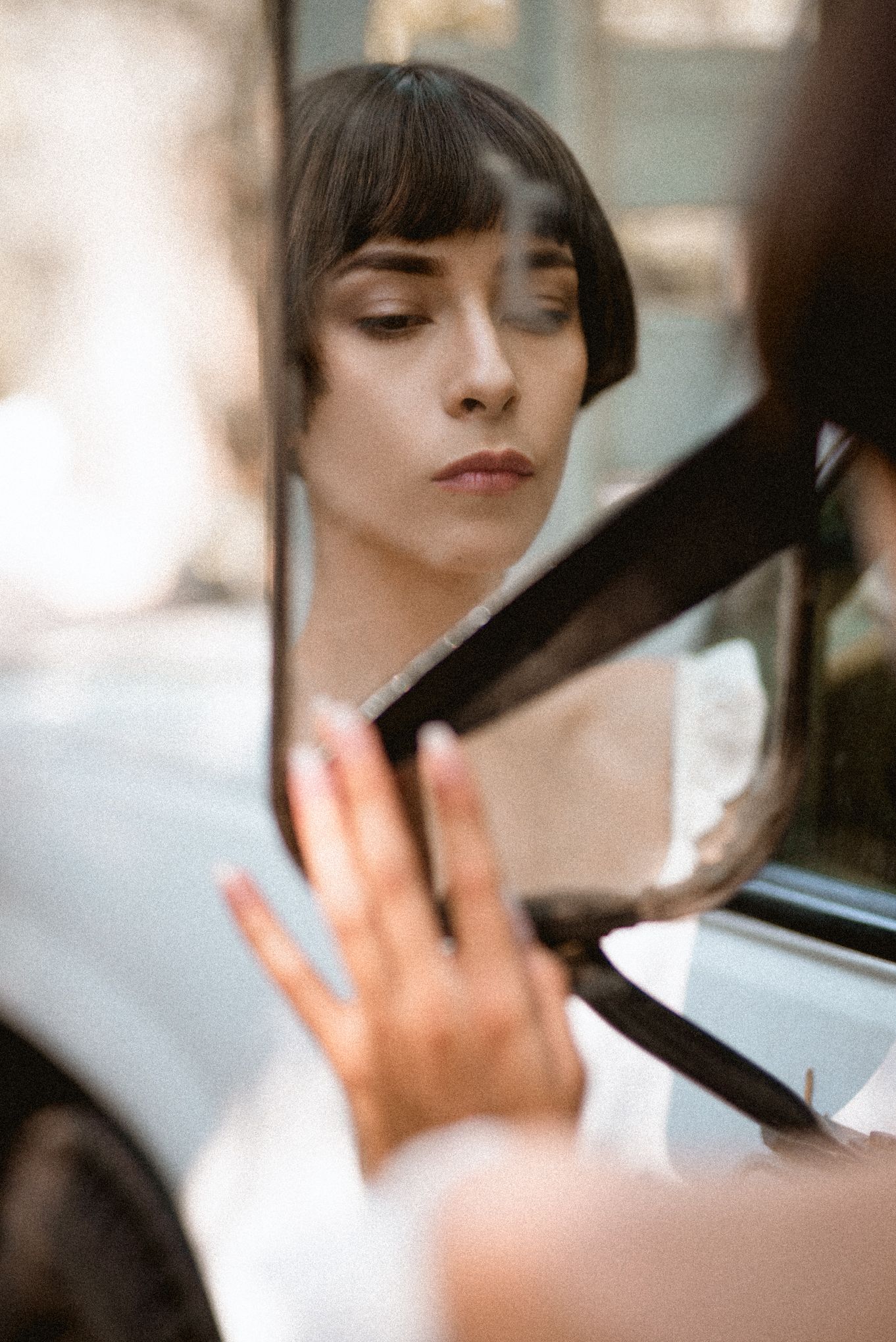 Vintage-style portrait reflected in car side mirror with soft focus.