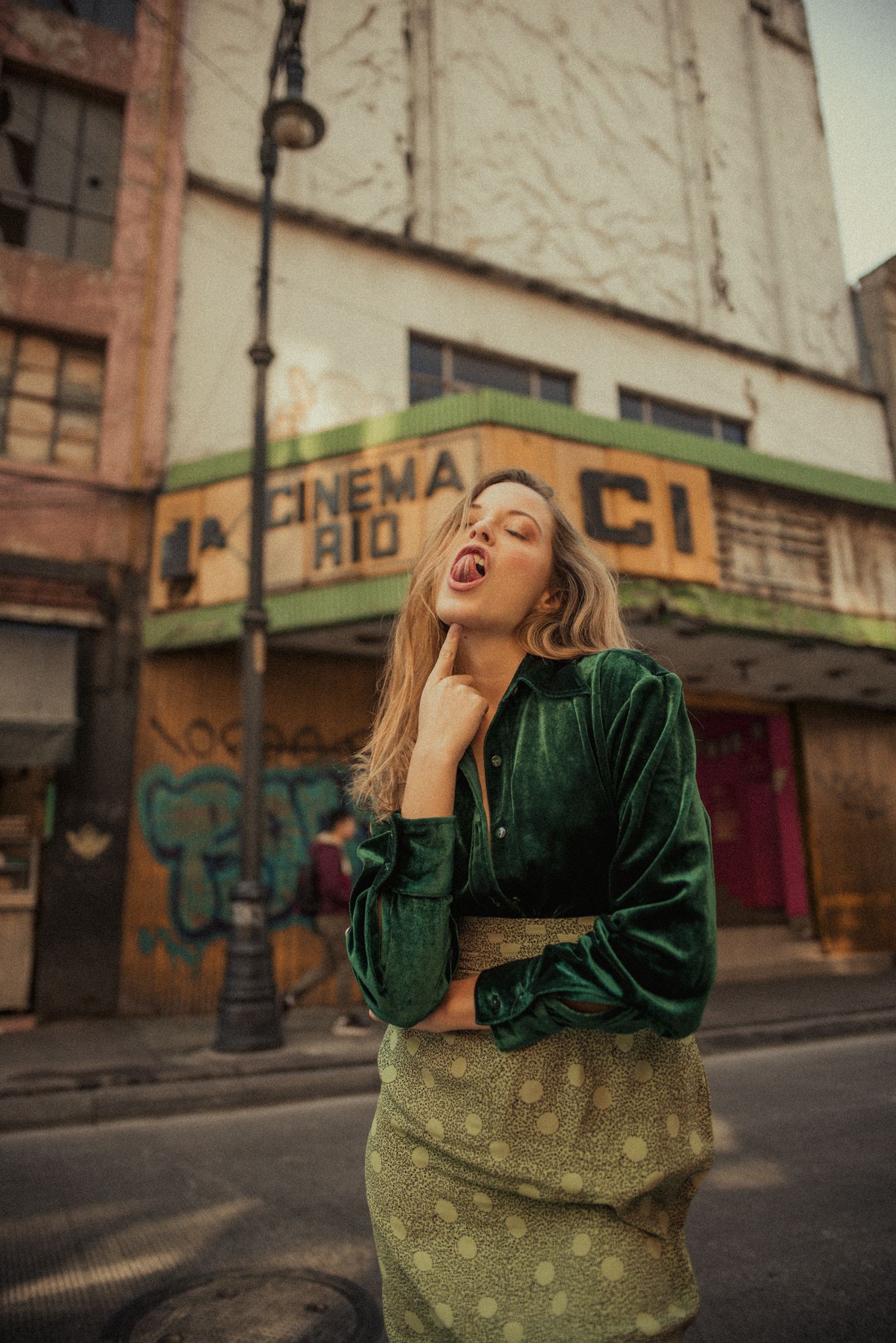 Urban fashion portrait in green velvet jacket outside vintage cinema building.