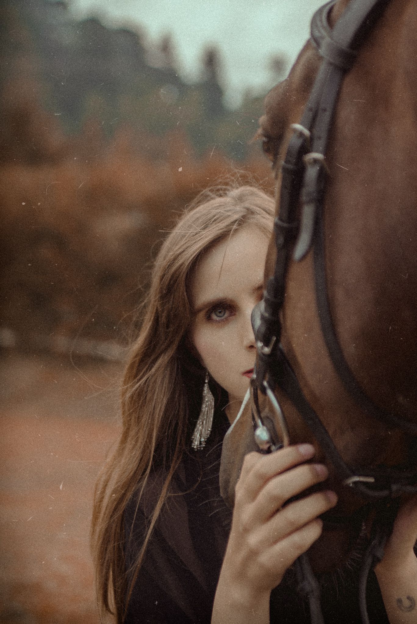 Moody portrait with horse in autumn setting featuring dramatic lighting.