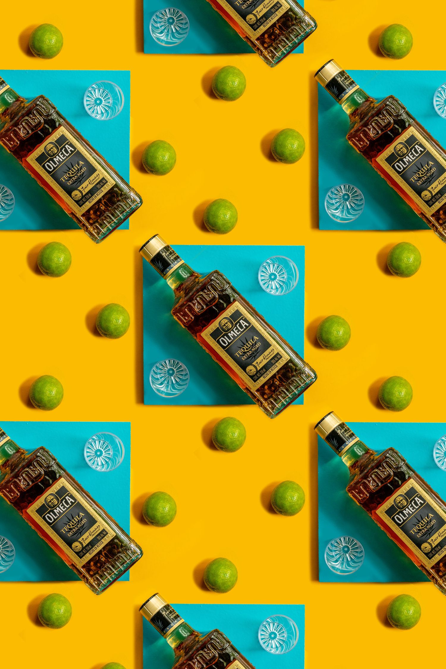 Repeating pattern of Olmeca tequila bottles with fresh limes on yellow and turquoise color blocks.