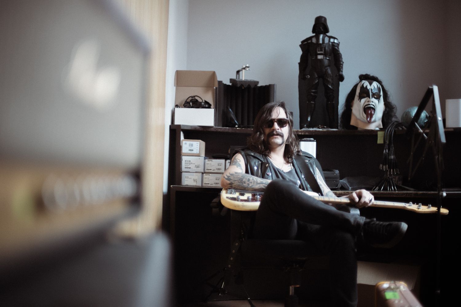 Musician relaxes in studio space with musical equipment and decorative items visible in background.