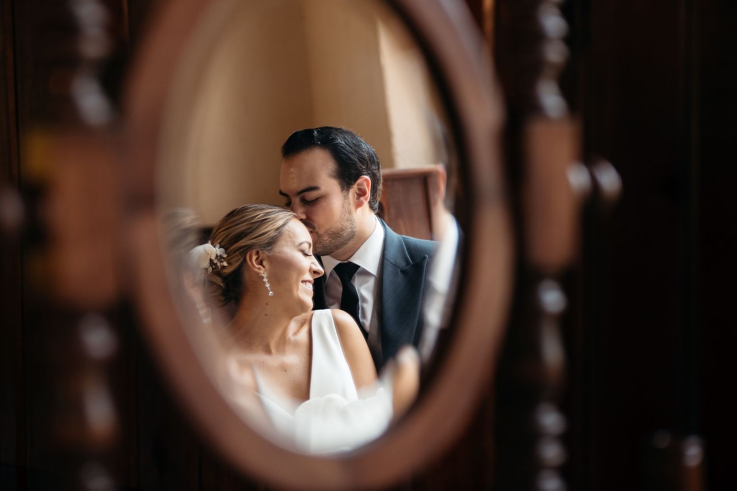 An intimate mirror reflection captures a tender wedding moment between a couple.