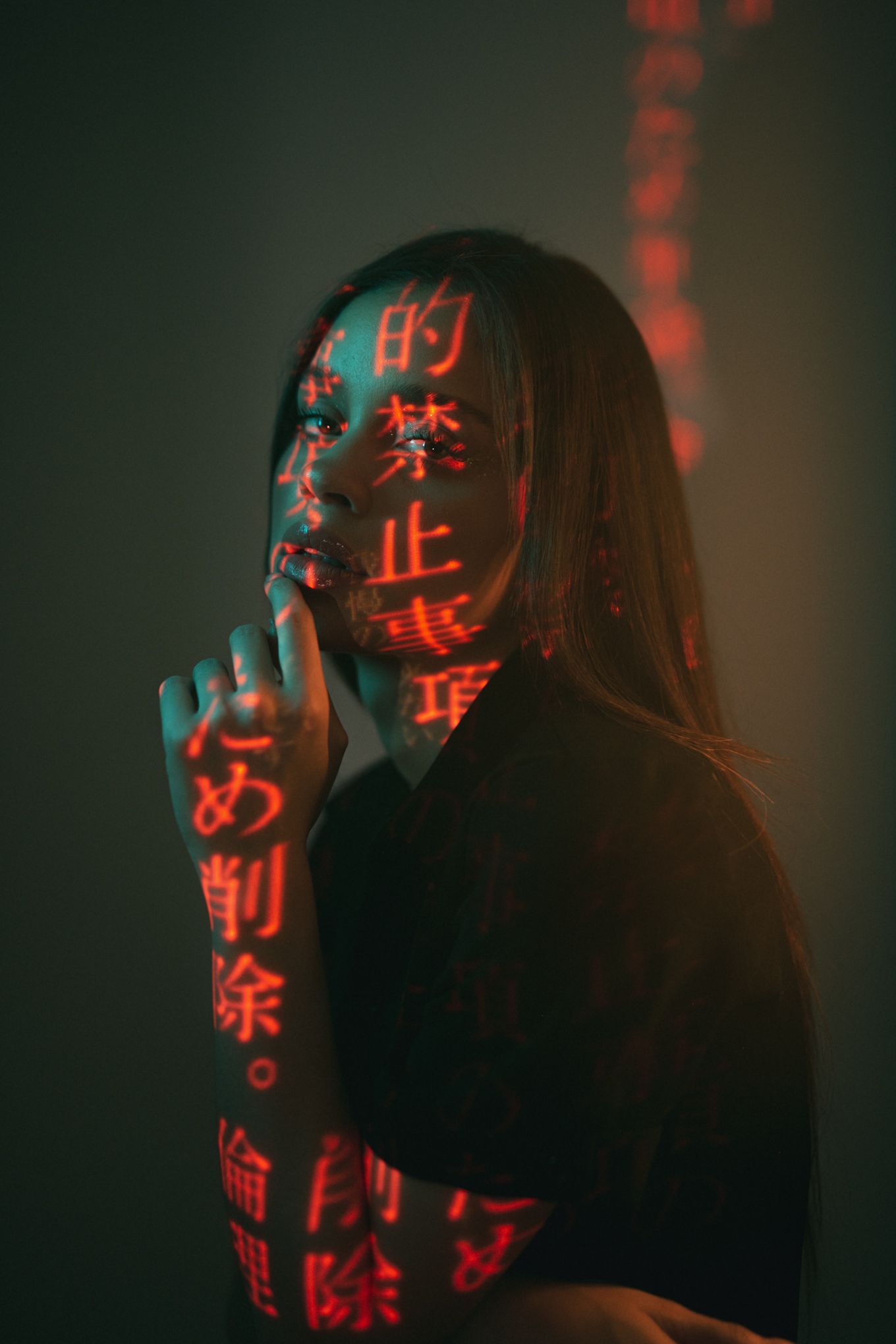 Silhouetted figure illuminated by red Chinese character projections in a dark atmospheric setting.