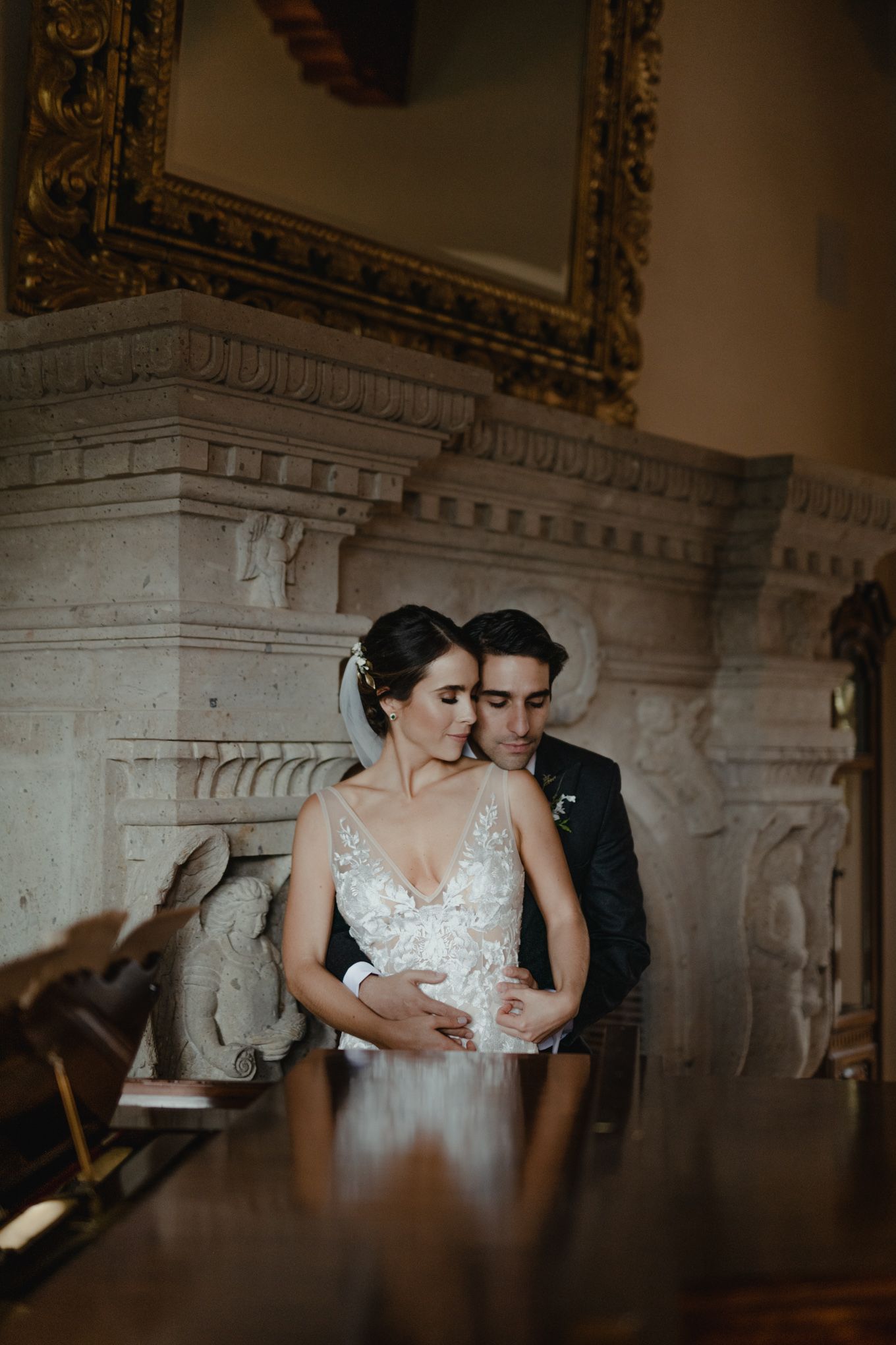 A romantic moment captured in an elegant interior with ornate architecture and a gilded mirror.