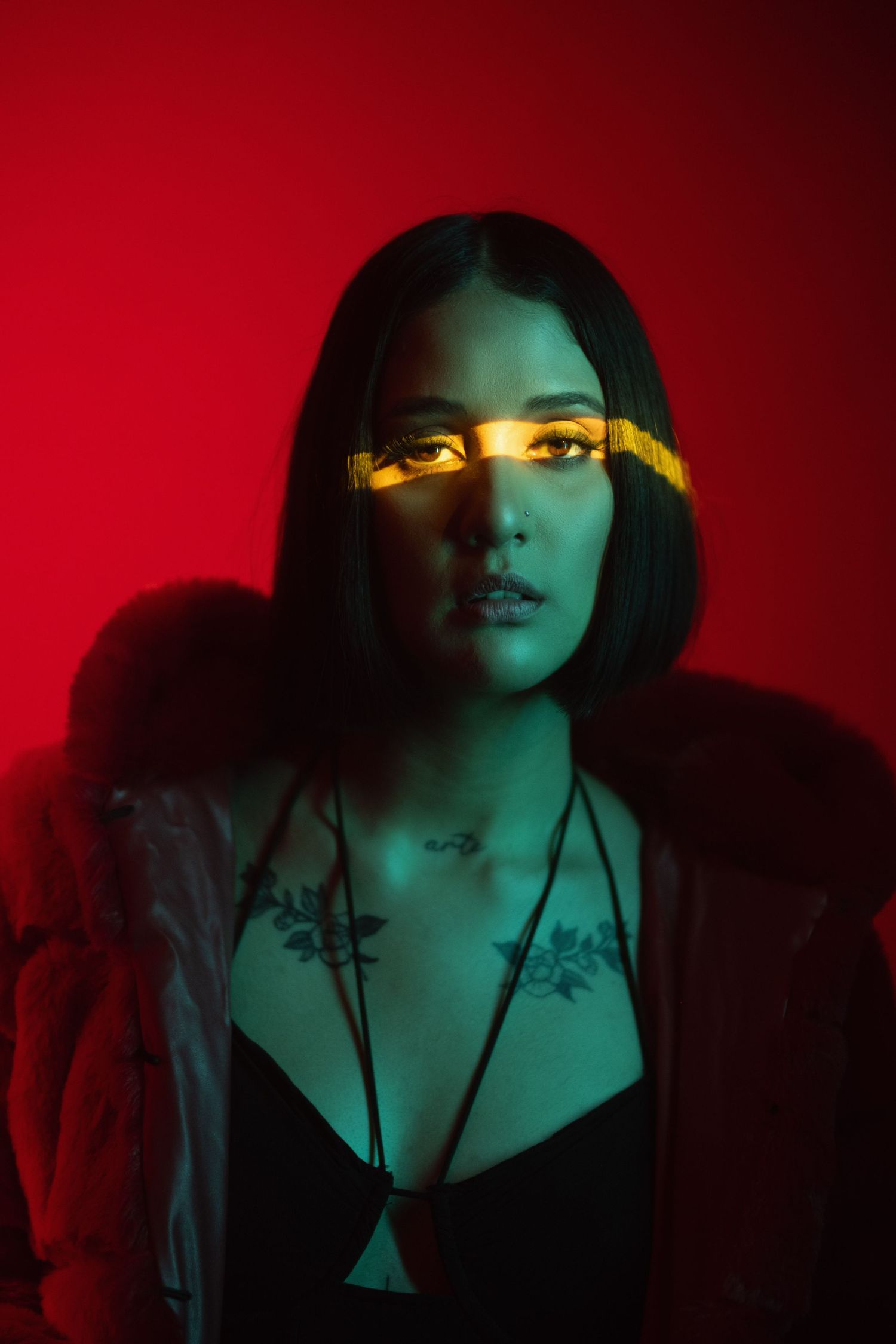 Dramatic portrait with neon yellow light strip across dark red background.