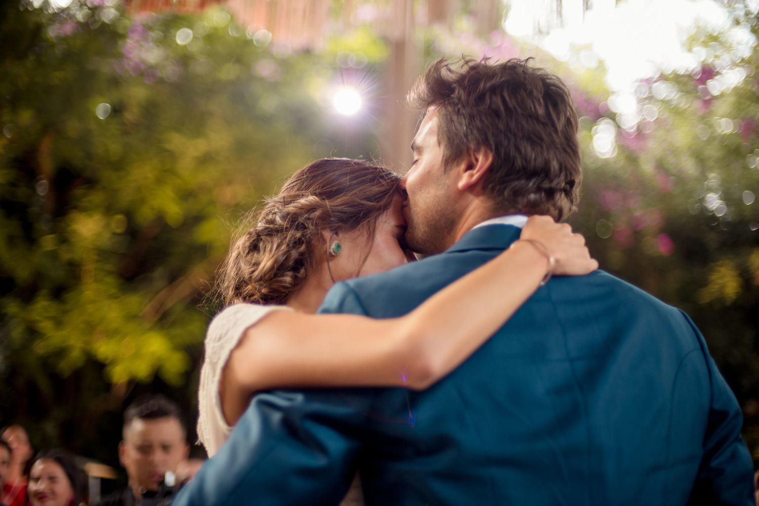 A tender embrace between newlyweds dancing outdoors with bokeh lights in the background.