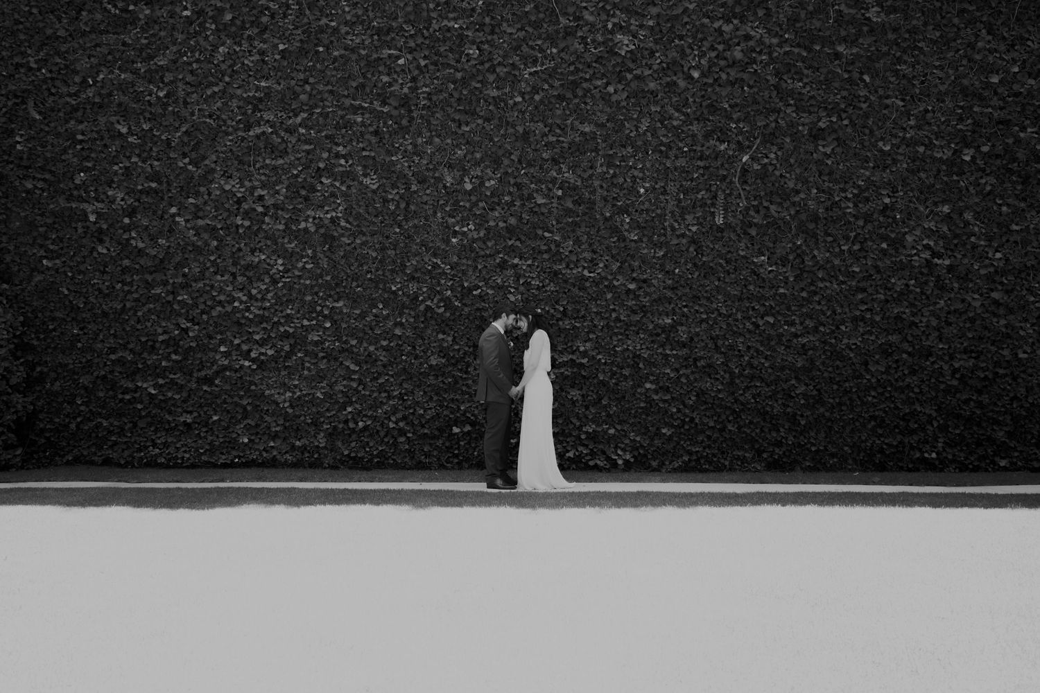Minimalist black and white wedding photo against geometric wall backdrop.