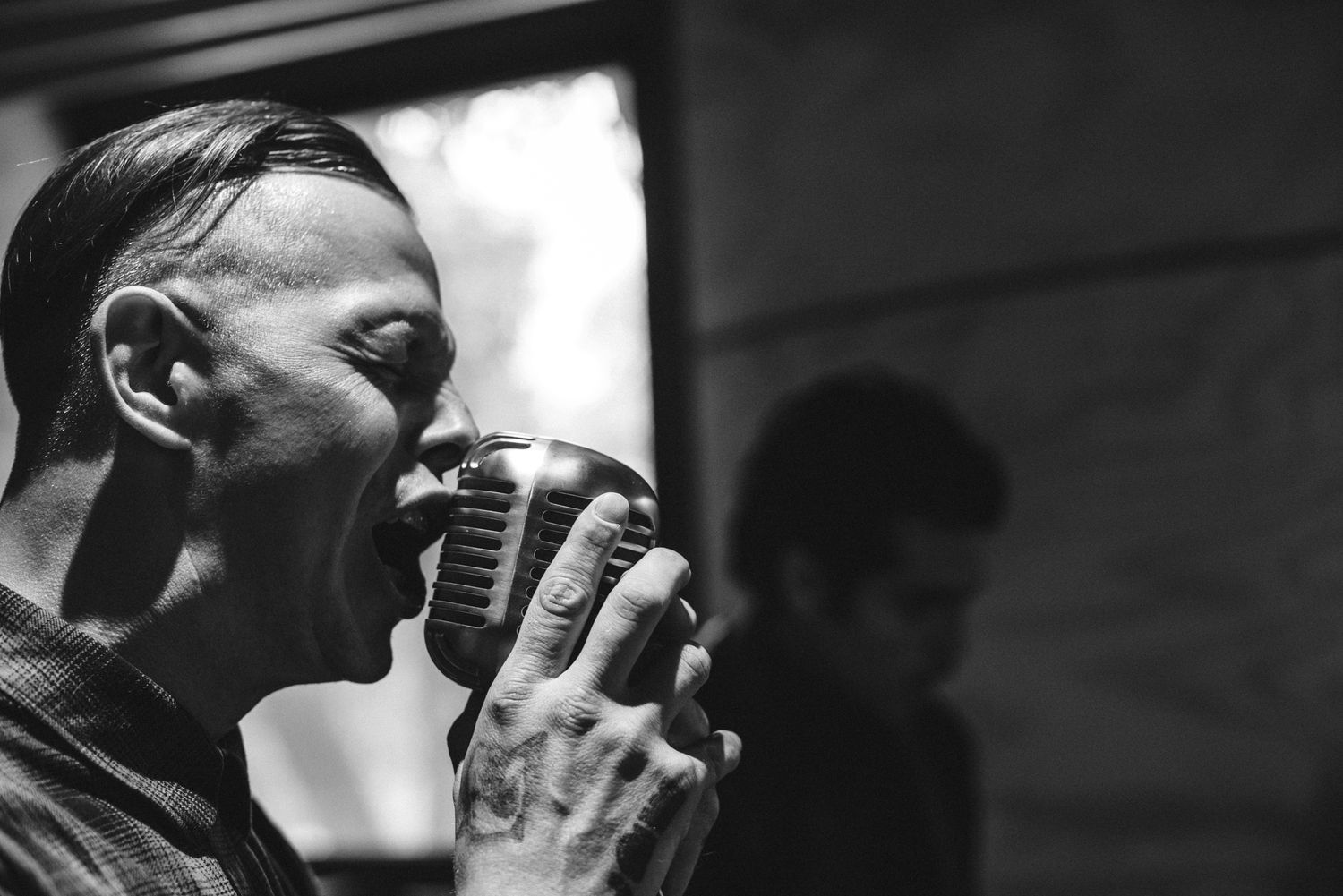 Close-up black and white portrait of vocalist singing into retro microphone.