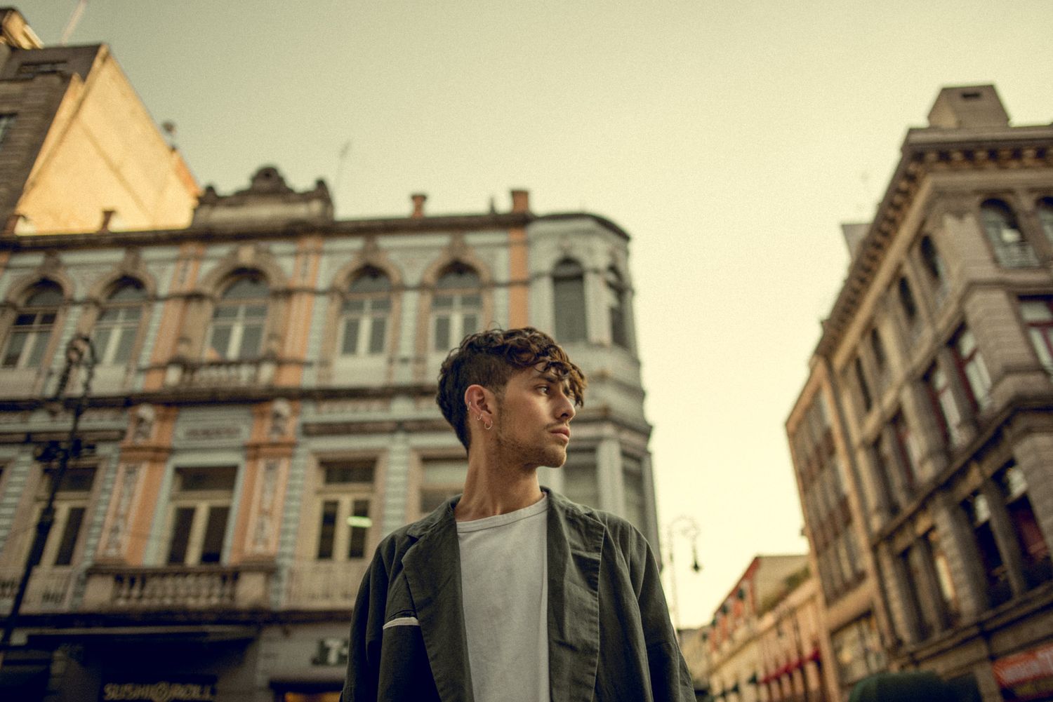 Stylish casual look against historic European city buildings at sunset.