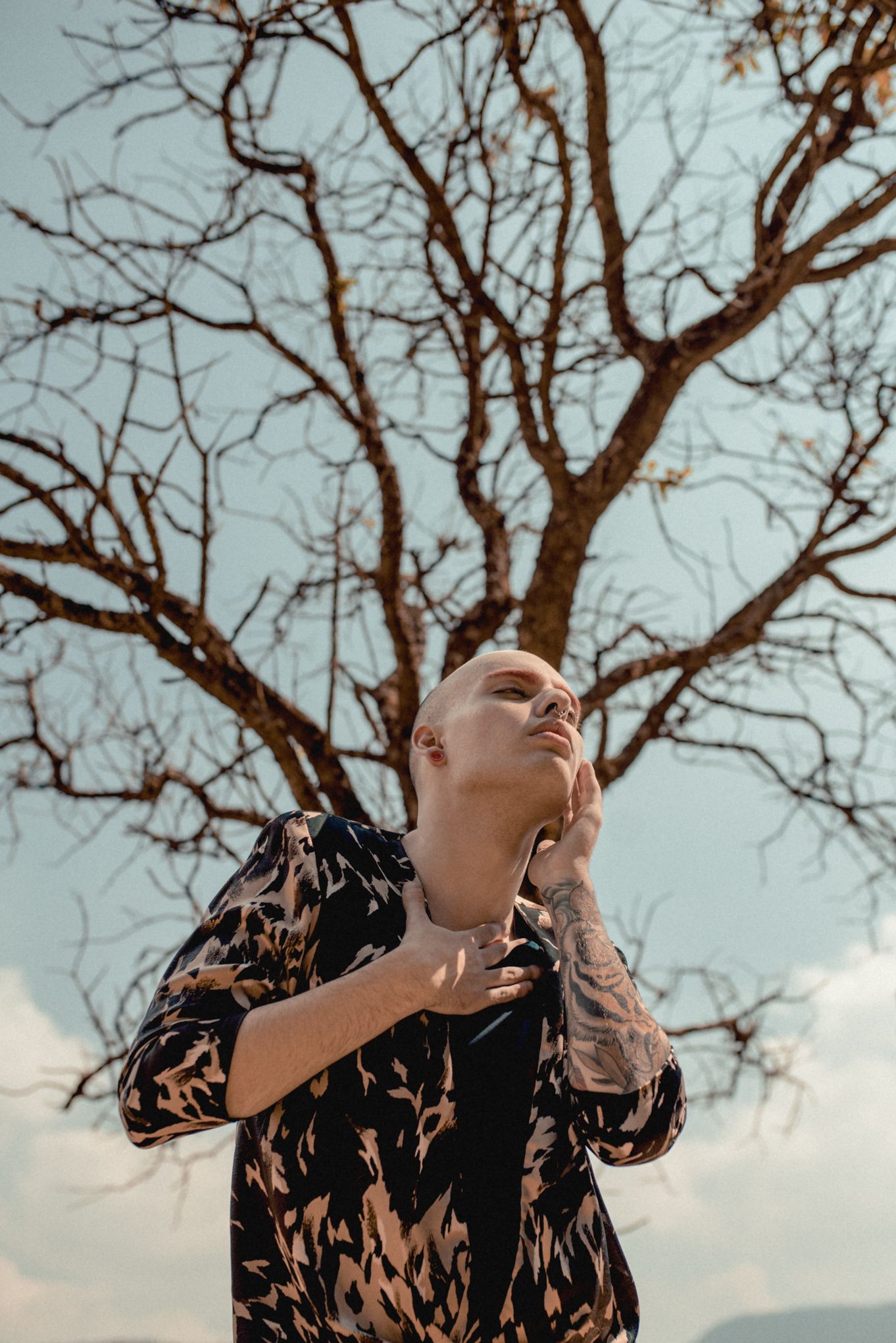 Artistic portrait featuring pattern clothing against bare winter tree branches.