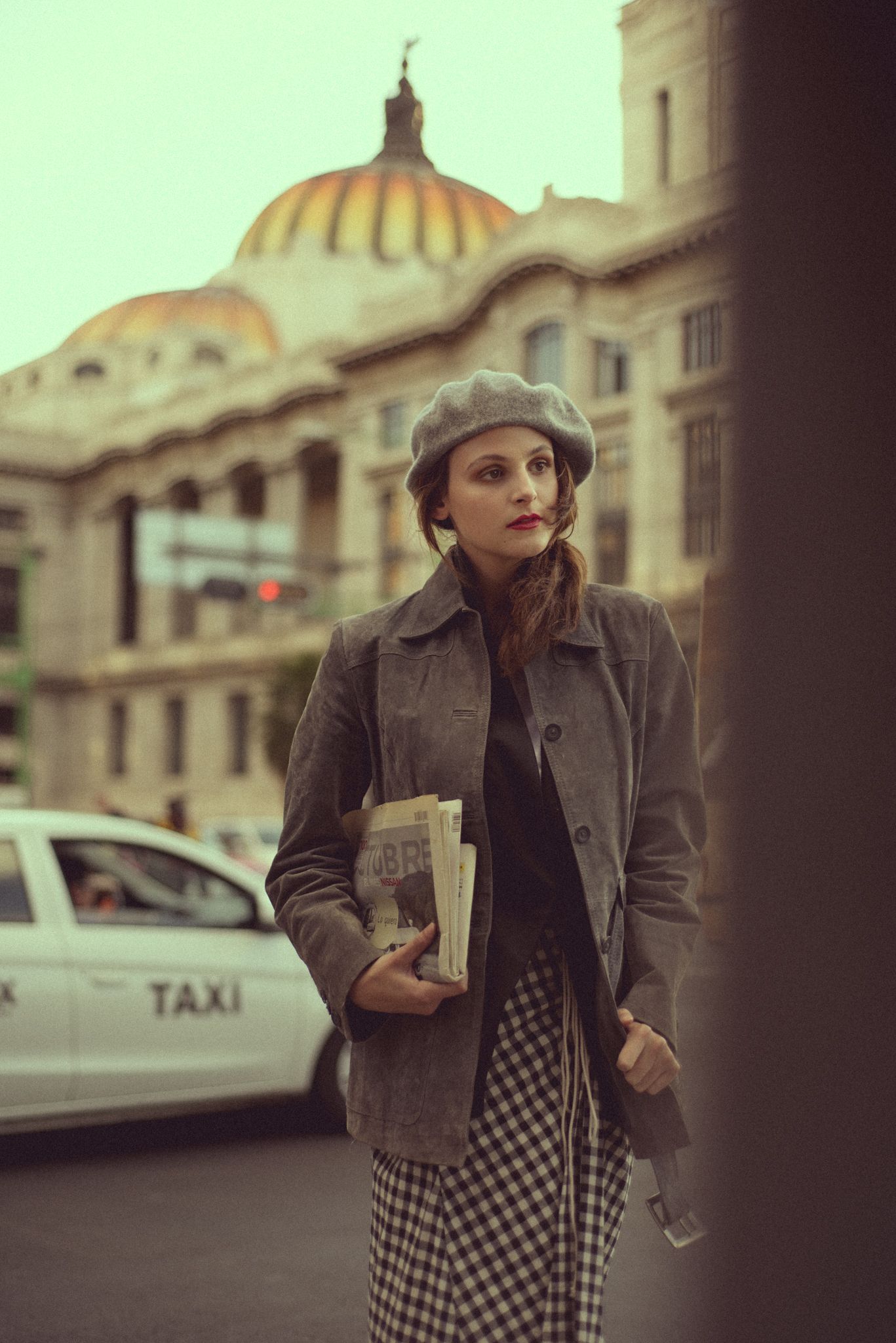 Cinematic fashion scene with domed architecture and taxi in background.