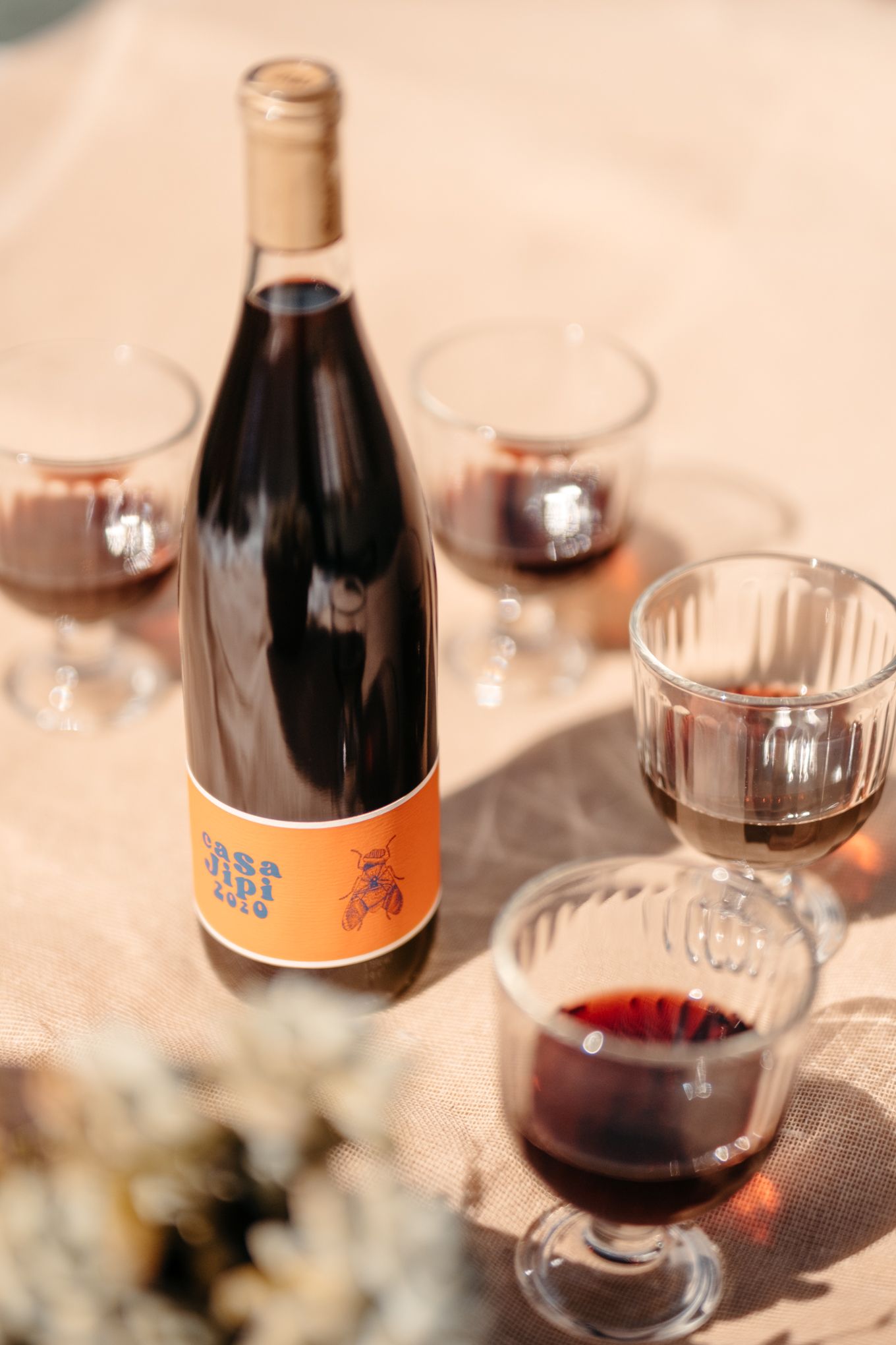 A closeup sequence of partially filled wine glasses and a dark craft beer bottle with an orange label in soft lighting.
