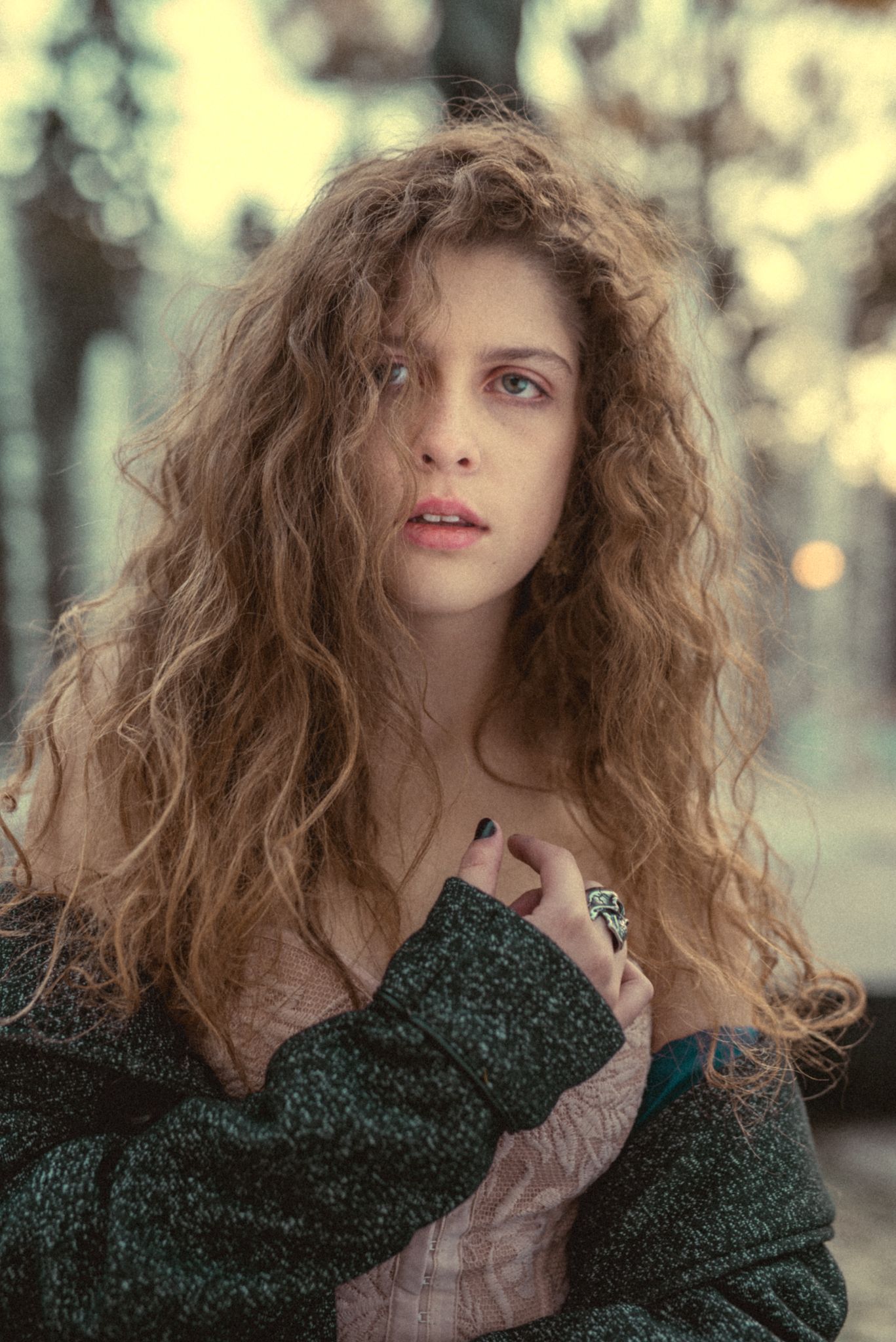 Romantic portrait showing textured curls and dark knit sweater in soft natural light.
