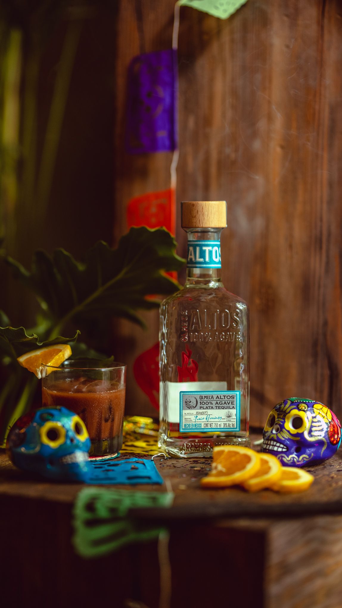 A set of five sequential photos showing tequila bottles with colorful party masks and orange slices in moody lighting.