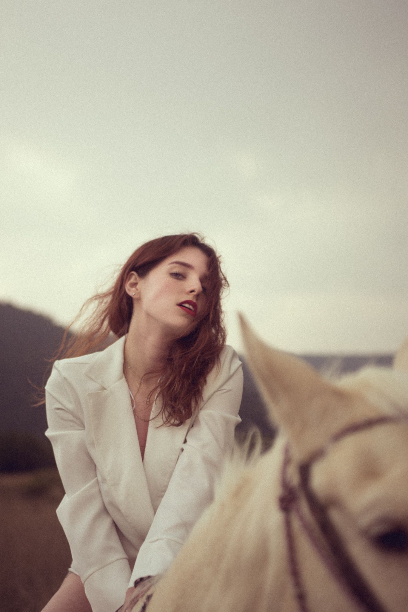 Ethereal portrait with white horse against overcast sky.