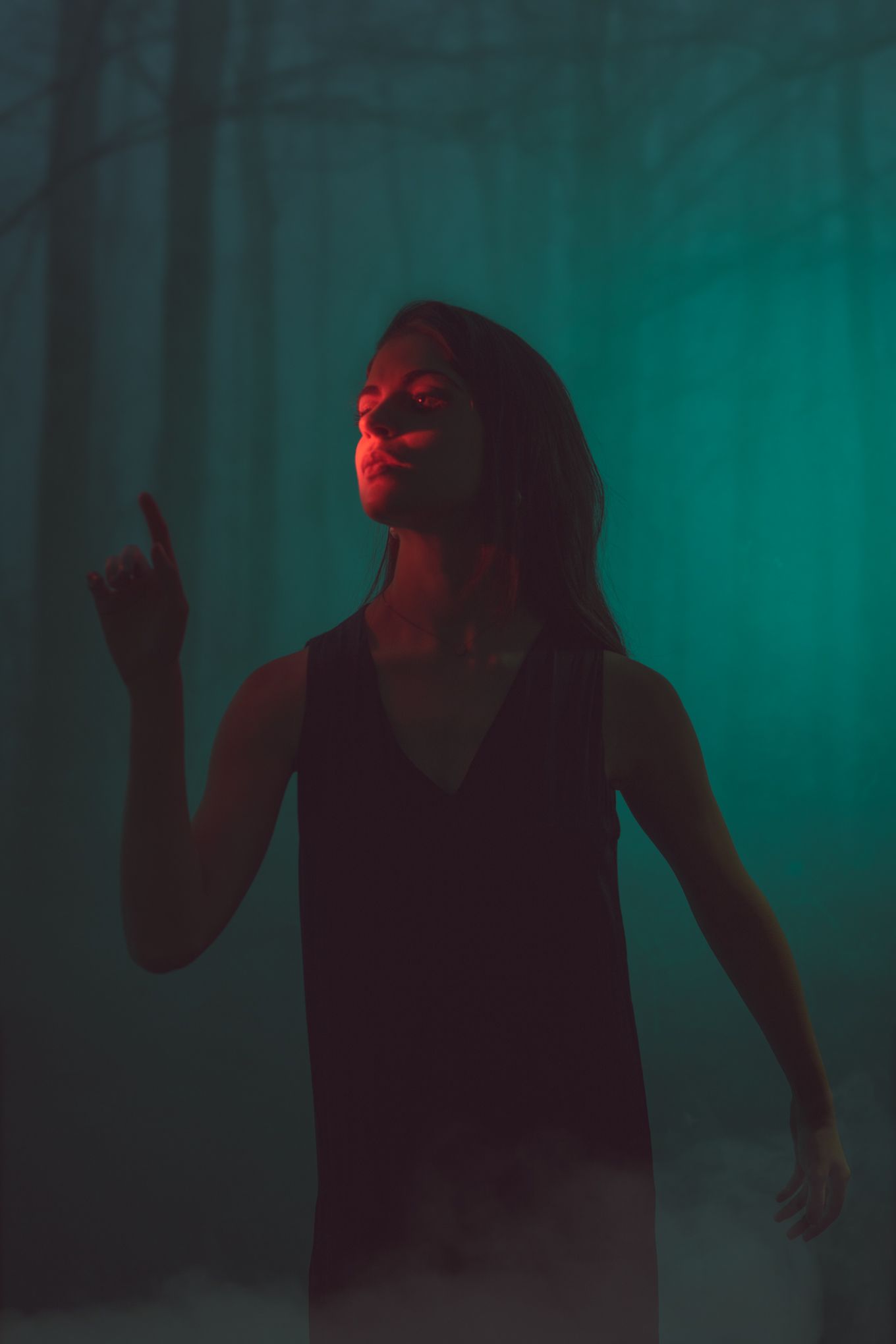 Silhouette in dark forest with dramatic red and teal lighting effects.