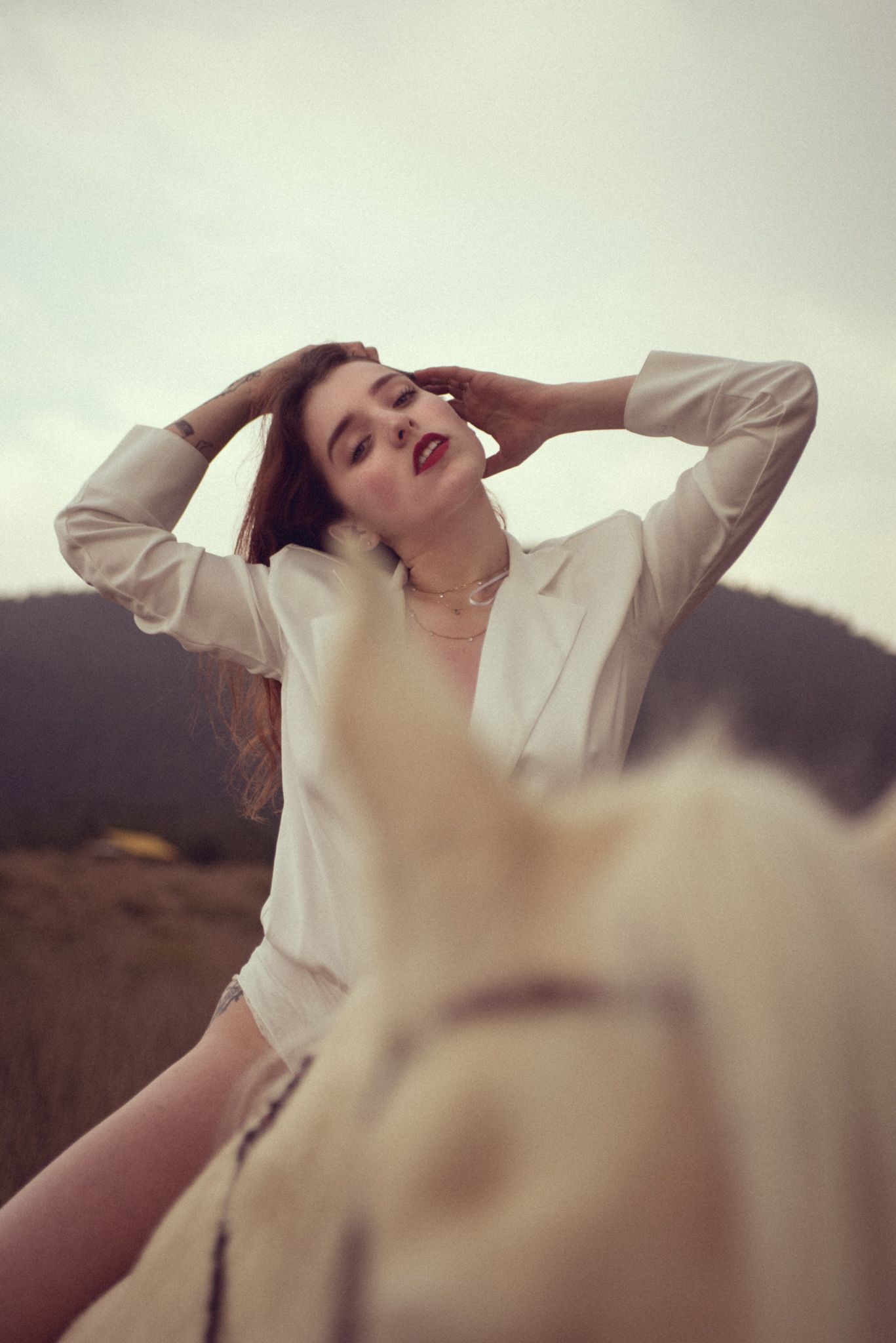 Dramatic portrait in cream clothing with mountains in background.
