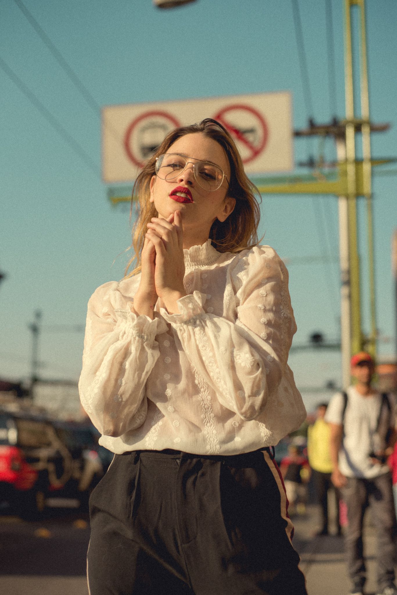 Dramatic street style portrait with white Victorian blouse and red lipstick against urban setting.