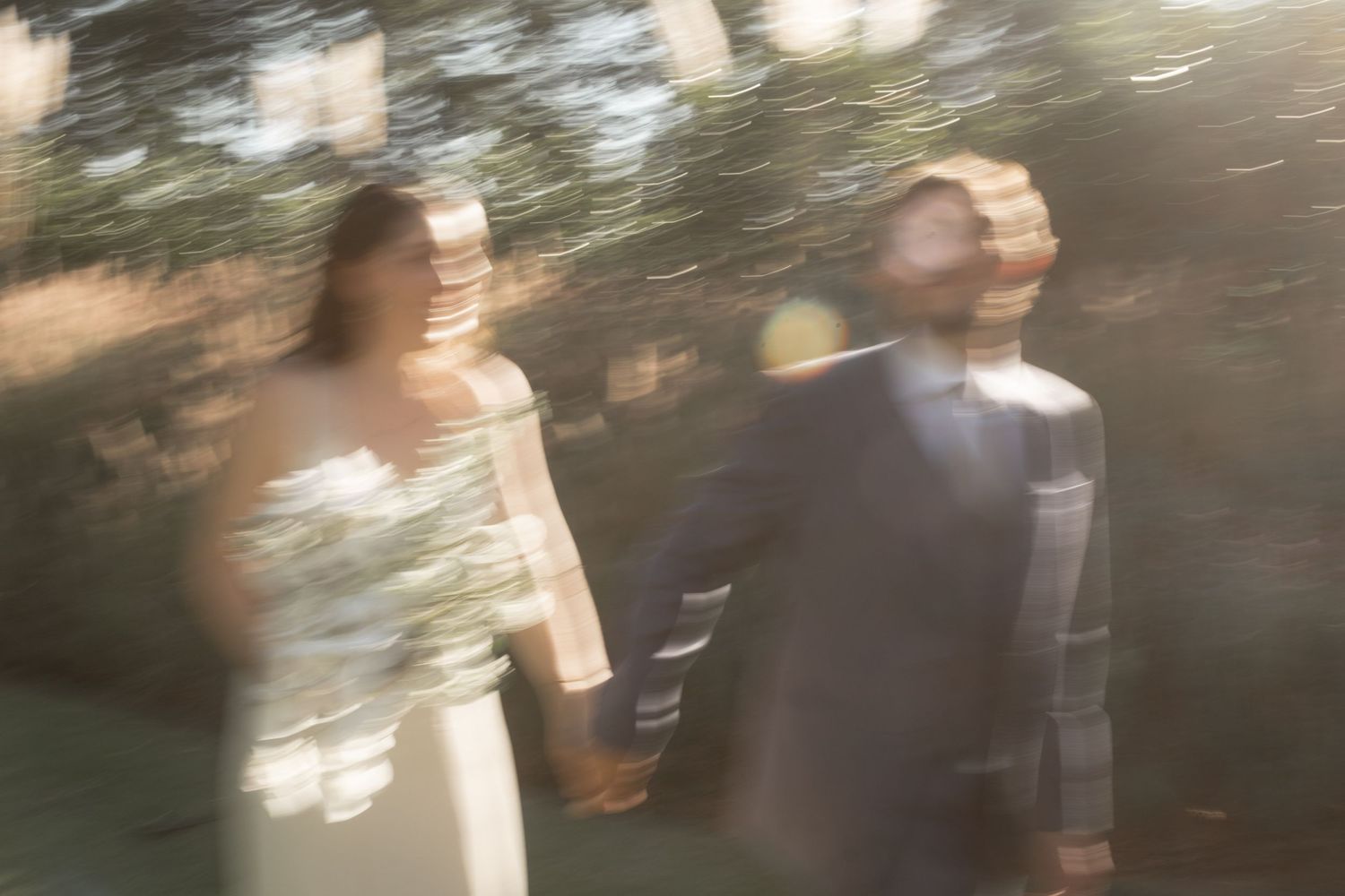 Artistic motion blur photo of wedding couple walking together outdoors.