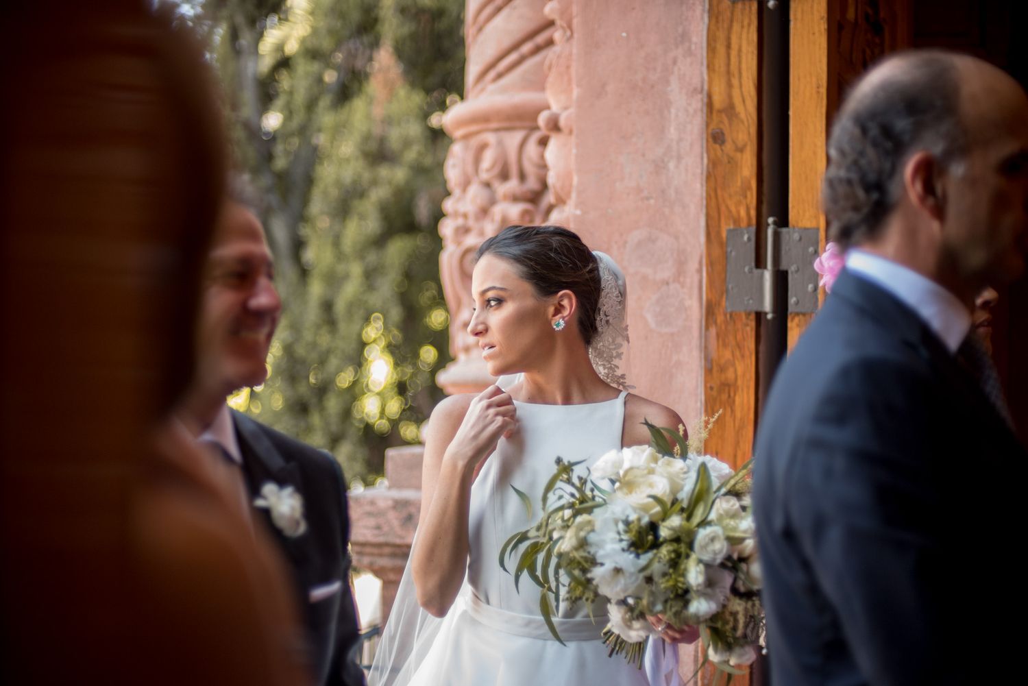 A quiet moment captured during a wedding ceremony against stone architecture and natural lighting.