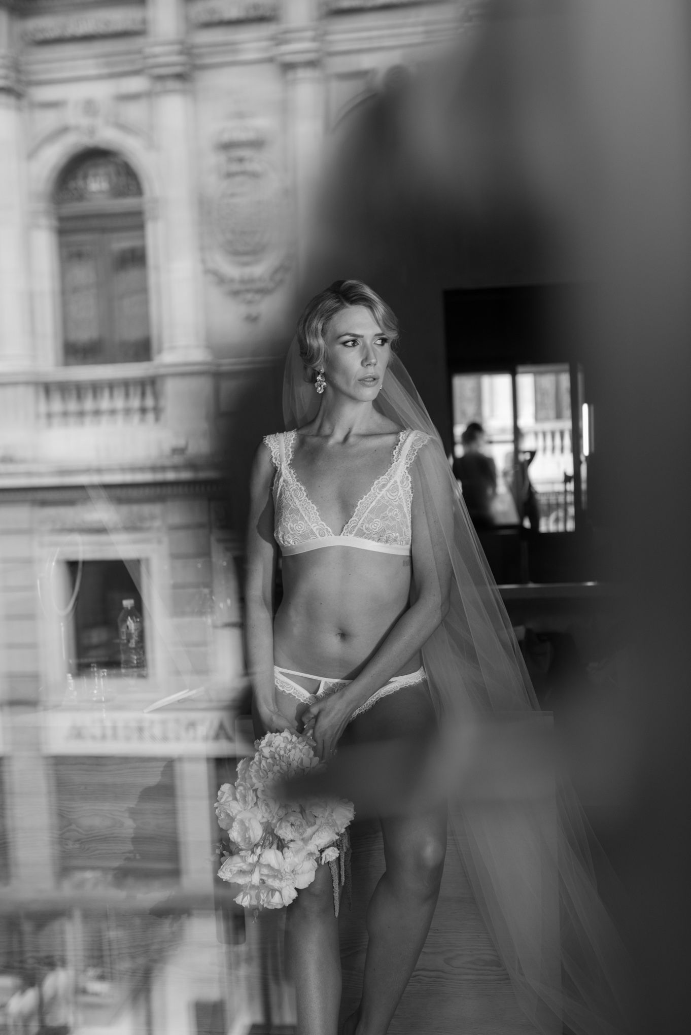 Artistic black and white bridal boudoir photo with architectural background.