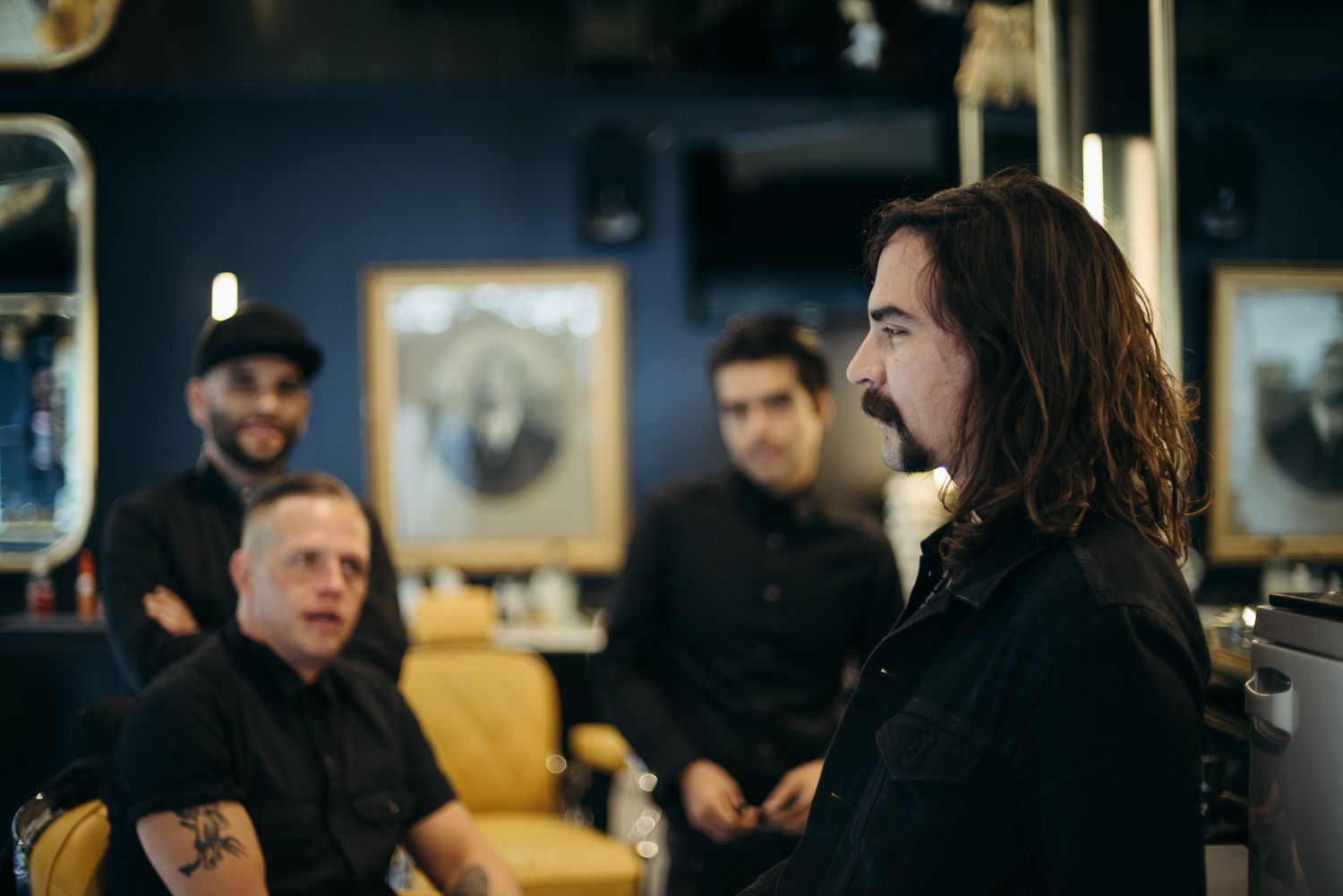 Group of people in dark clothing conversing in modern salon setting.