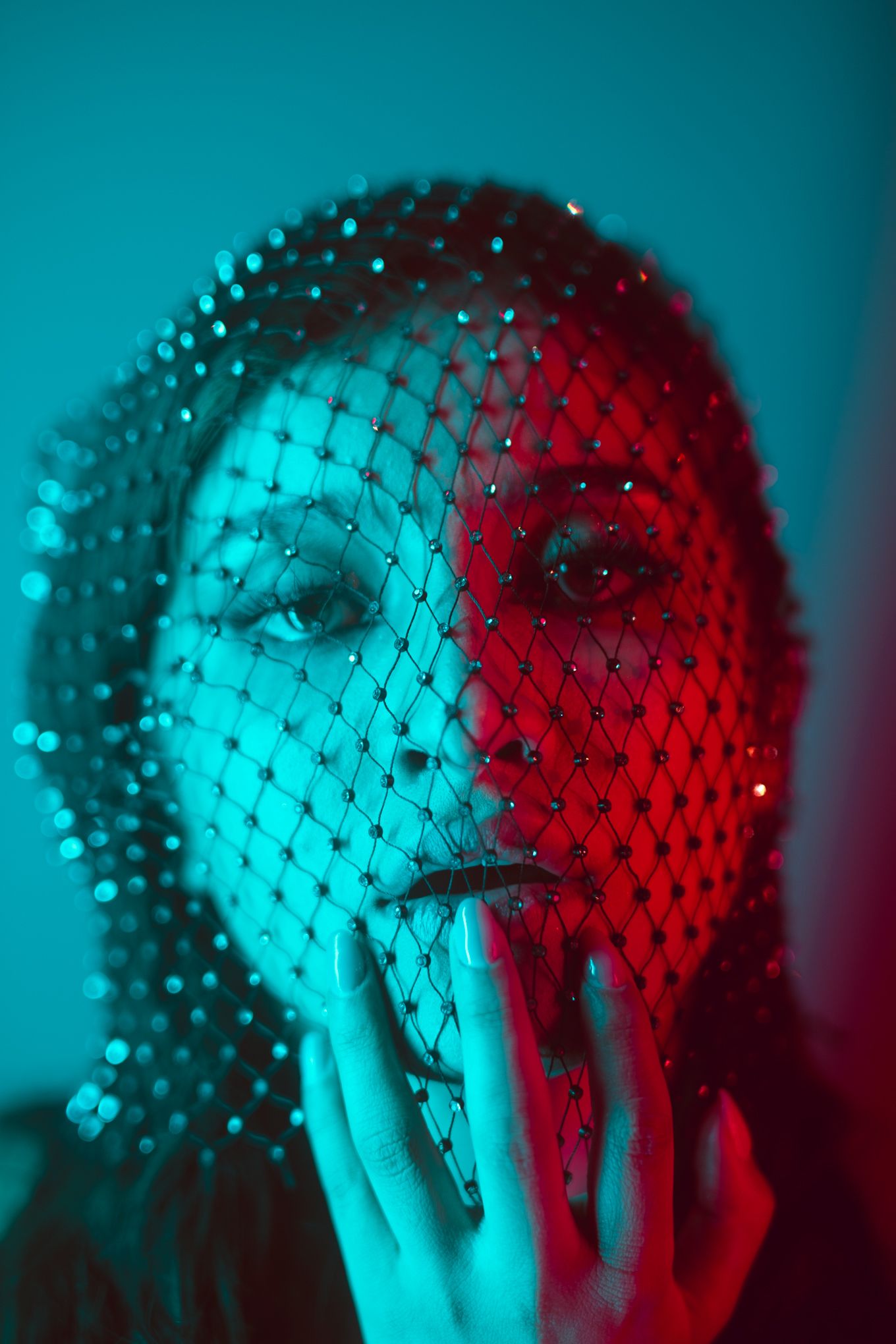 Striking portrait with dual-colored lighting and sparkly mesh veil creating geometric patterns.