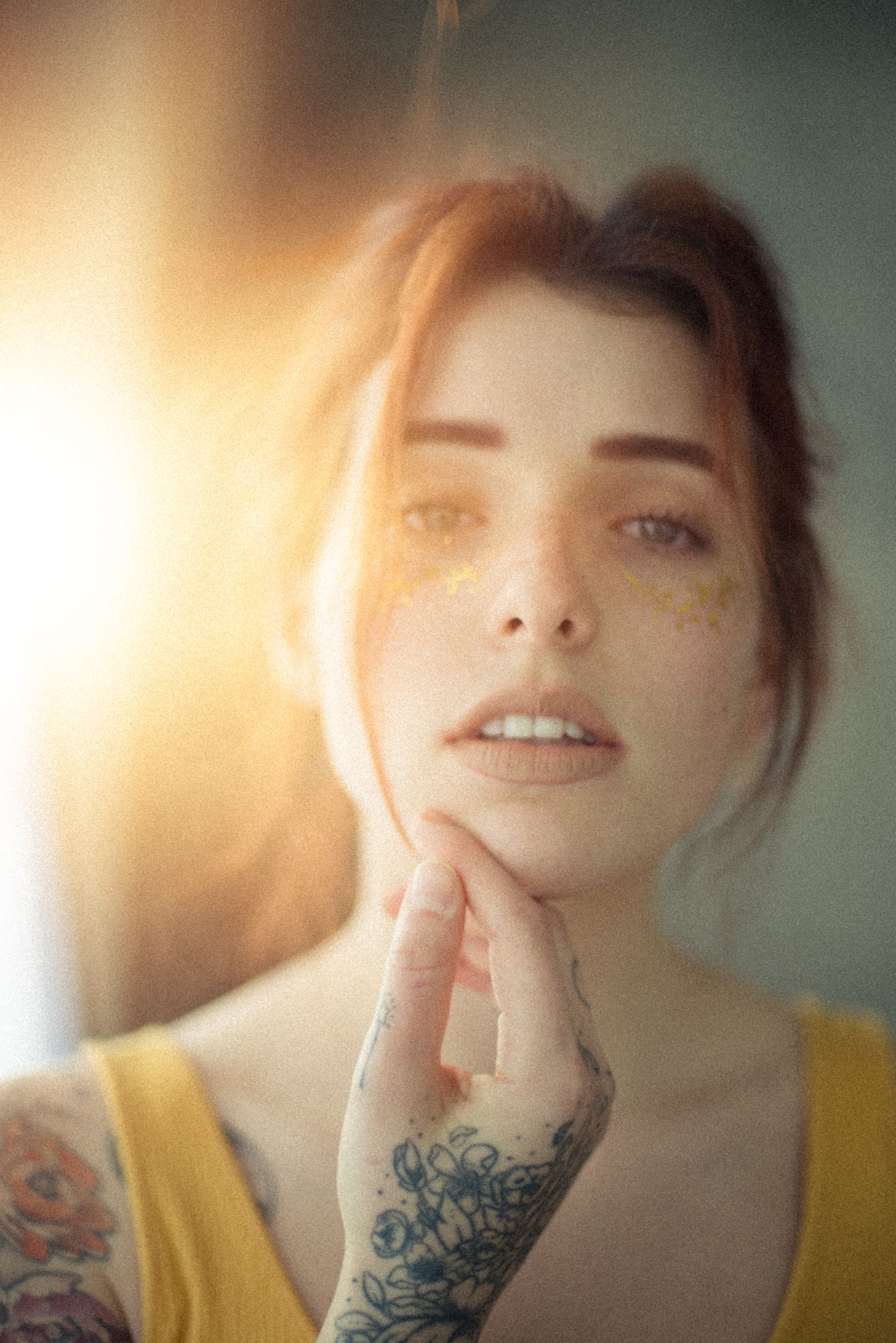 Close-up portrait with glowing sunlight and visible tattoo detail.