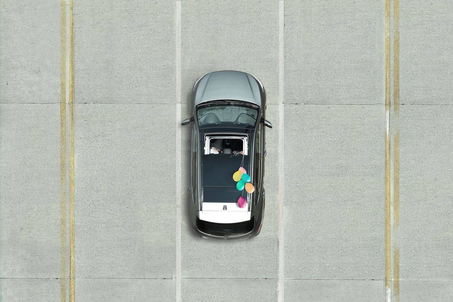 Aerial view of cars parked in orderly spaces with clean white lines against a light background.