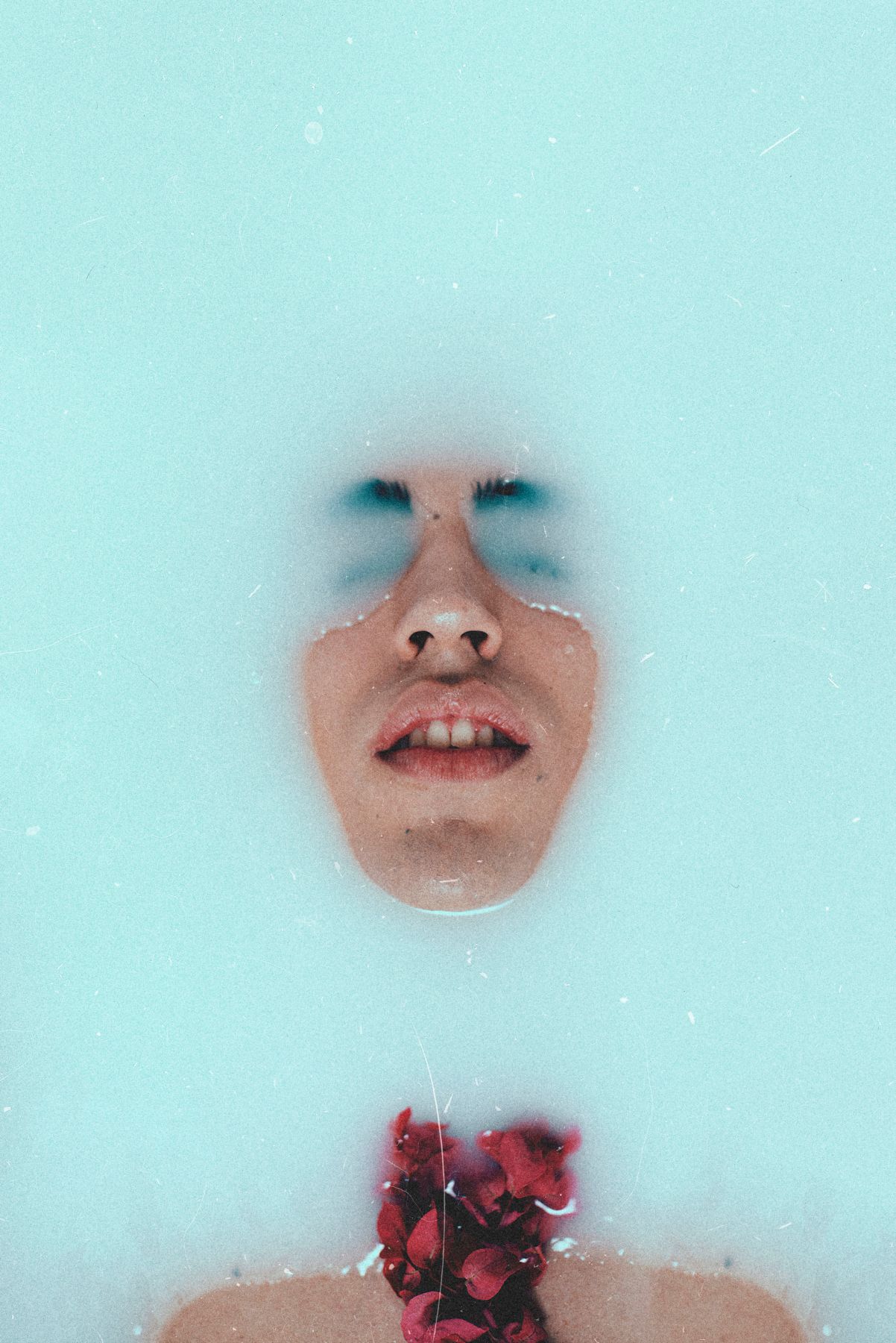 Minimalist portrait against turquoise background with red flowers and foggy effect.