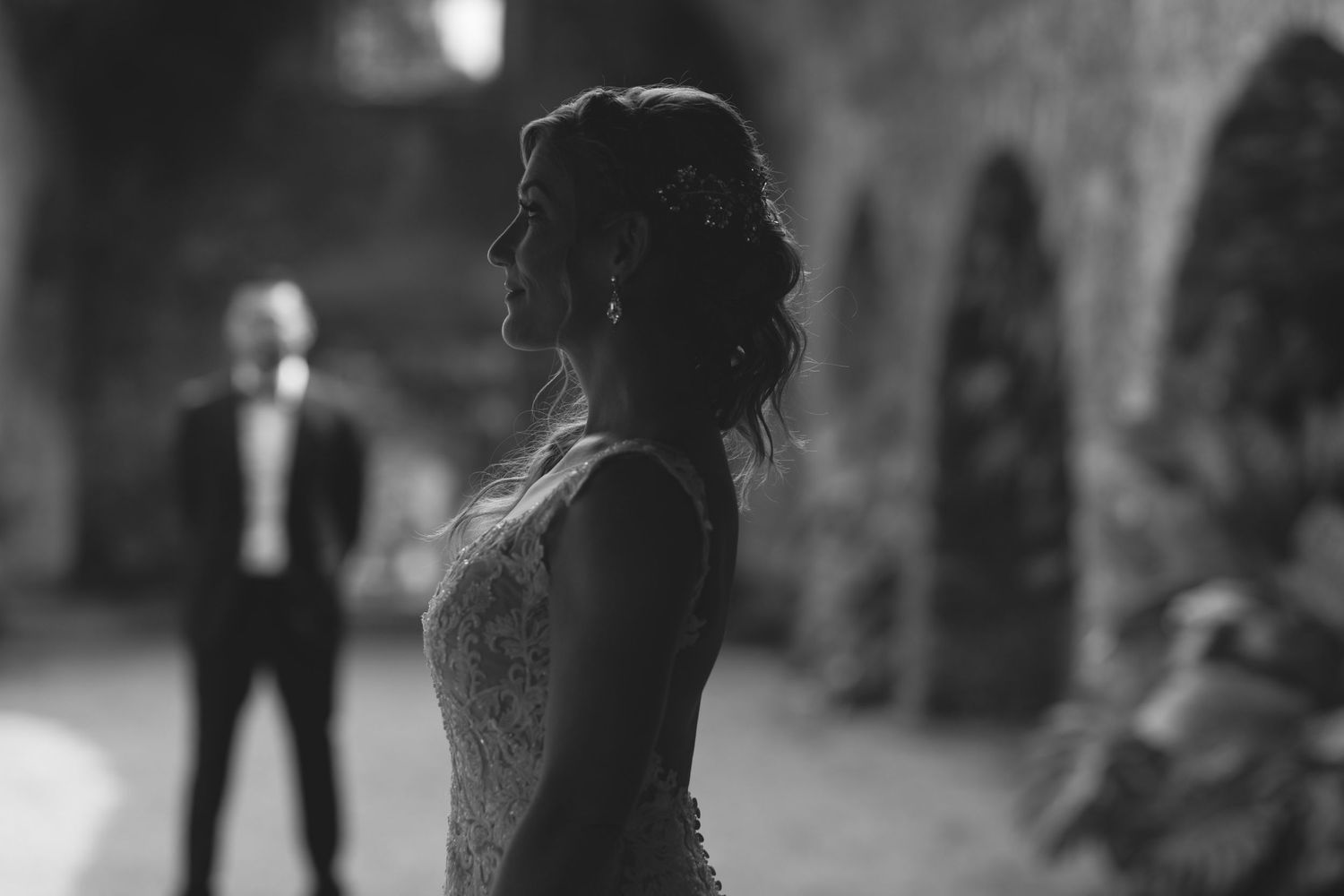 Dramatic silhouette of couple at romantic distance in dim vintage archway.