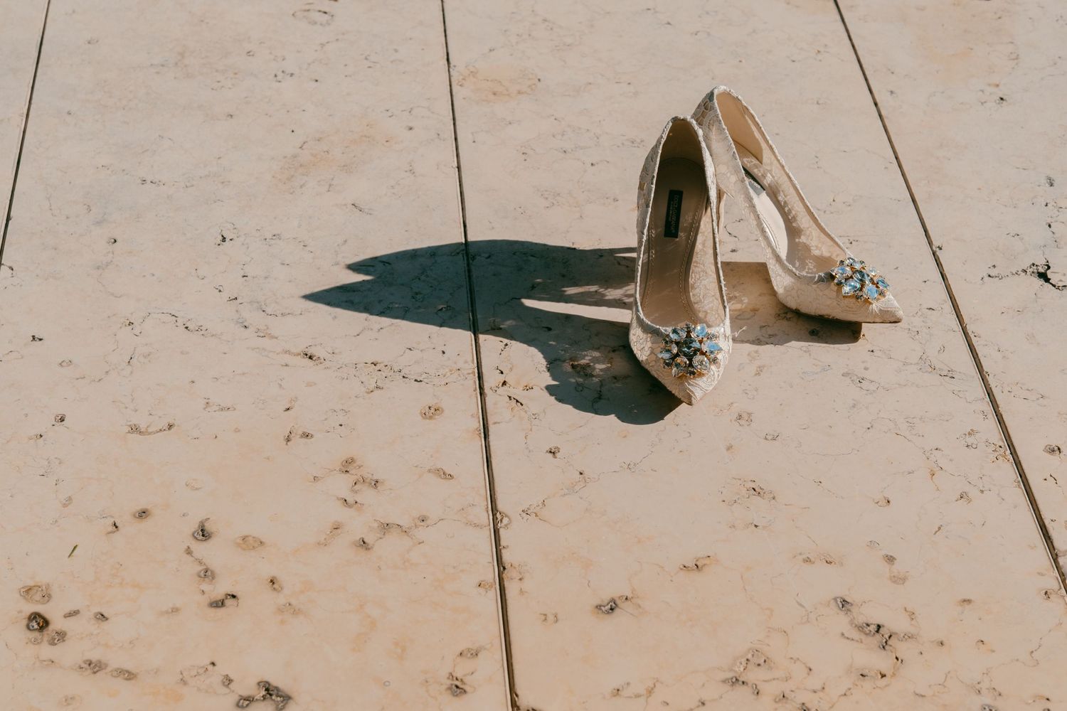 Sparkly wedding heels casting shadow on light colored floor.