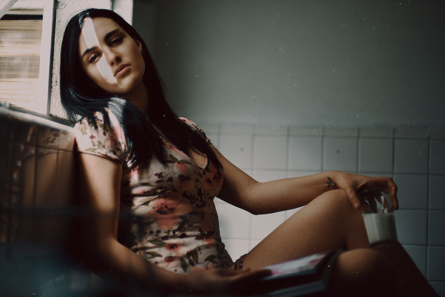 Moody portrait in bathroom with vintage color grading and dramatic shadows.
