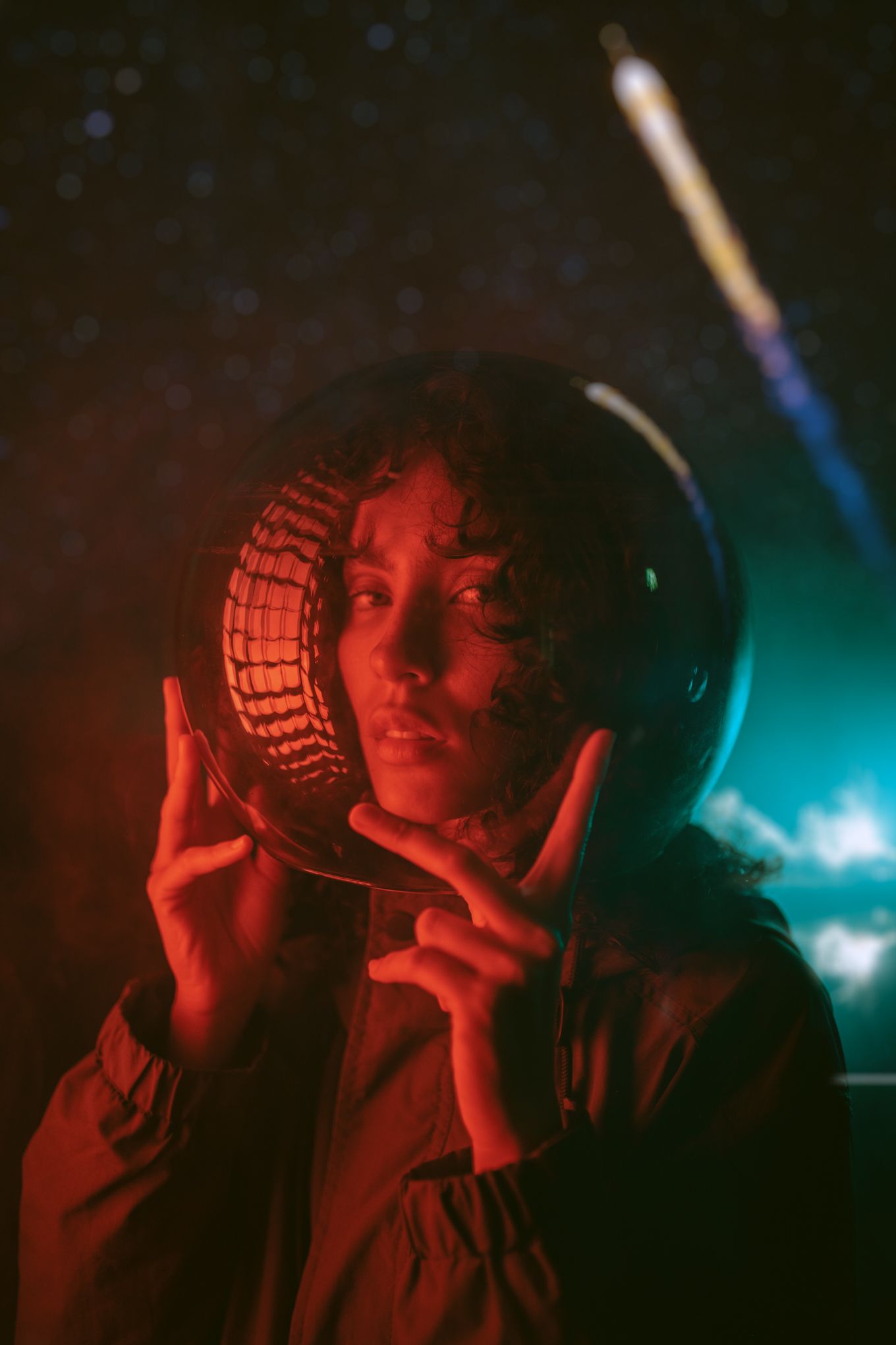 Person holding reflective disco ball in dark setting with red and blue mood lighting.